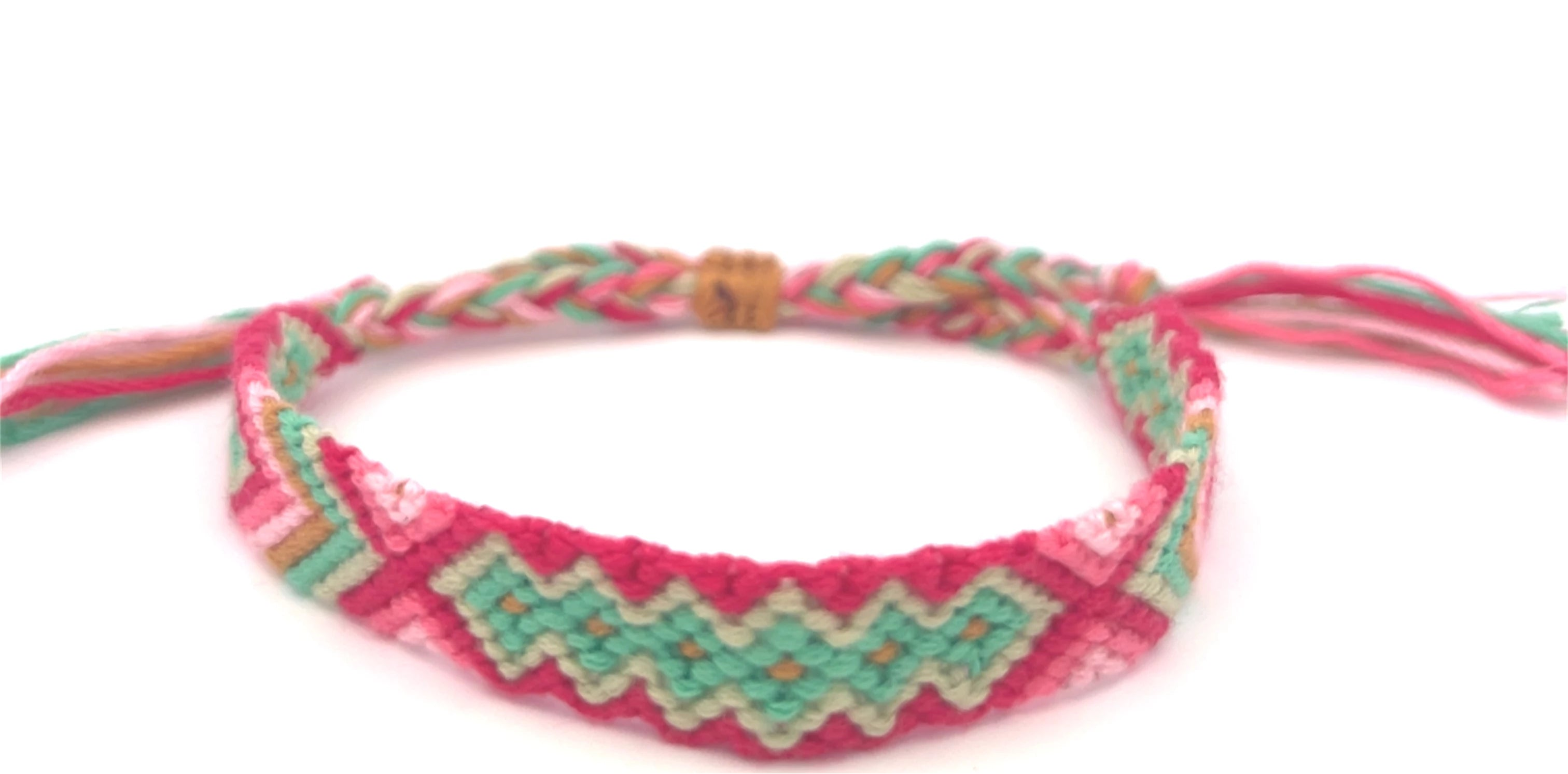 Pink and green braided friendship bracelet on a white background