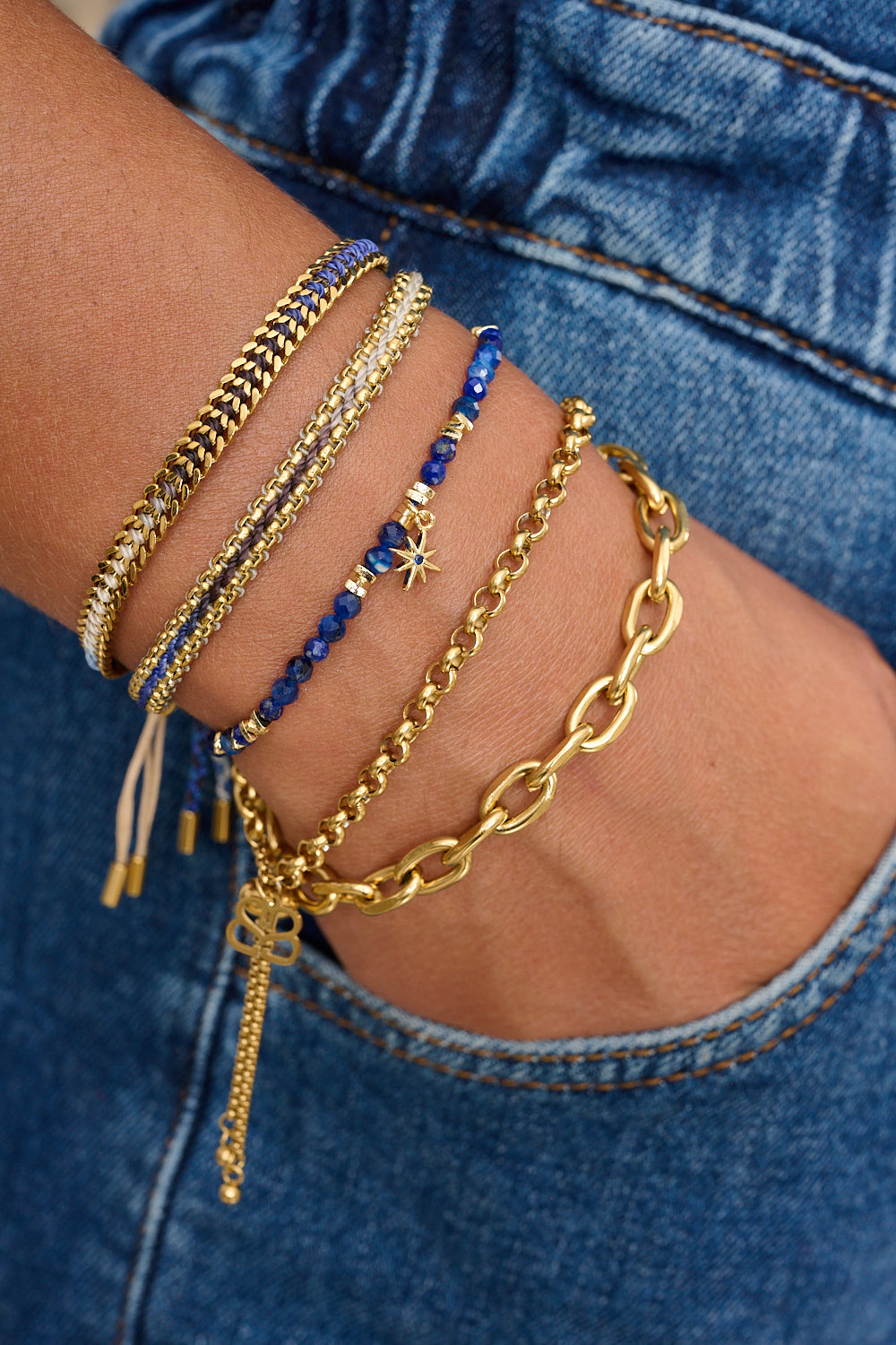 Bloom Denim Gold Braided Bracelet styled on the wrist, featuring a blue ombre thread and gold chain accents, ideal for summer adventures or everyday wear.