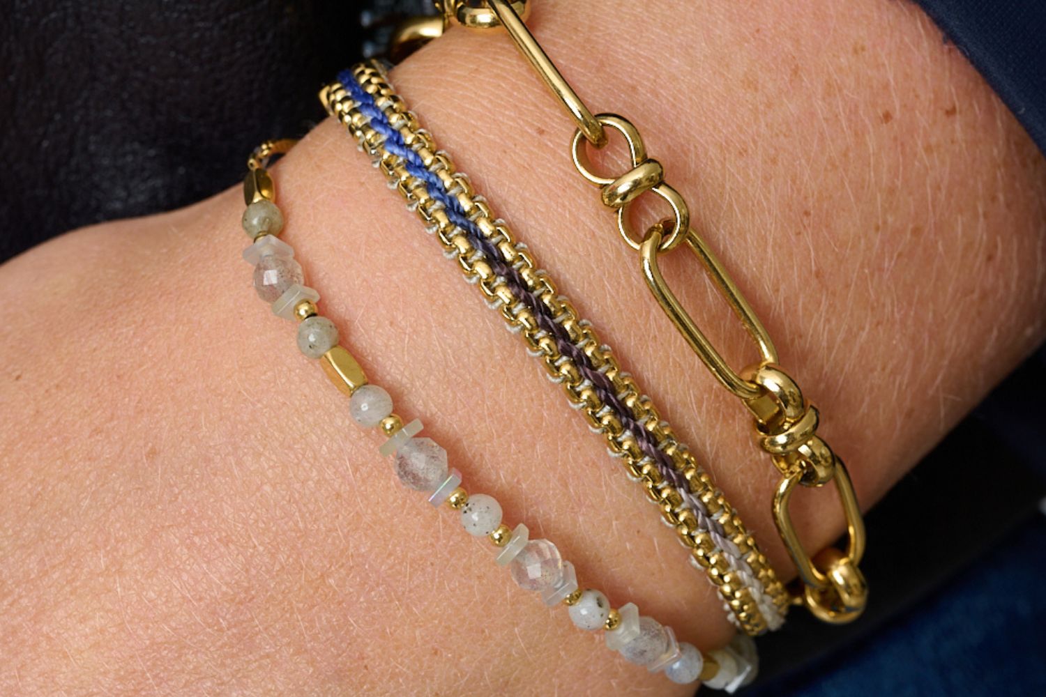 Bloom Denim Gold Braided Bracelet styled on the wrist, featuring a blue ombre thread and gold chain accents, paired with the Aya labradorite gemstone bracelet and gold link bracelet. ideal for winter and summer adventures or everyday wear.