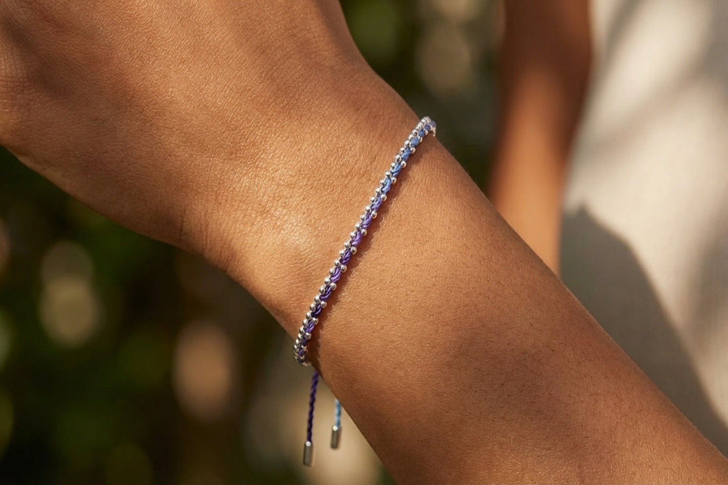 Close-up of female model's wrist wearing Braid Midnight Silver Woven Bracelet, highlighting braided threads and sterling silver chain.