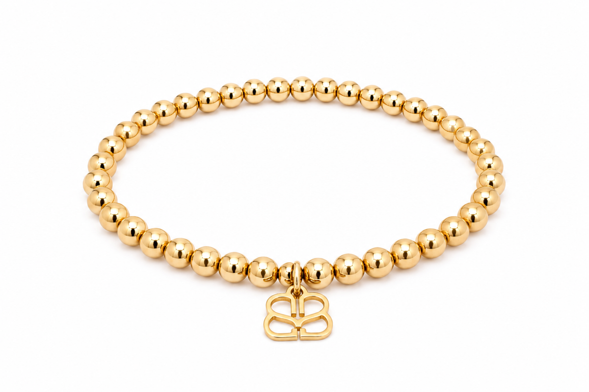 Cleo Gold Bead Stretch Bracelet featuring smooth polished gold beads, a signature BB filigree charm and waterproof 14k Gold PVD-coated stainless steel.