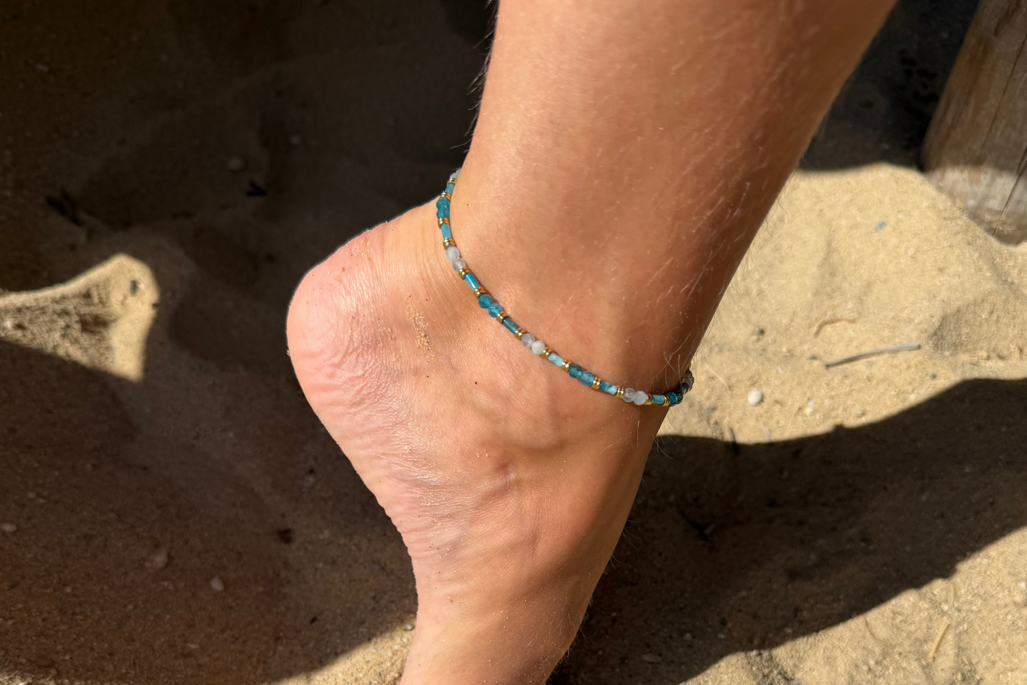 Coralie Apatite & Aquamarine Gold Anklet worn around the ankle with natural Apatite and Aquamarine gemstones and a waterproof 14k Gold PVD stainless steel chain.