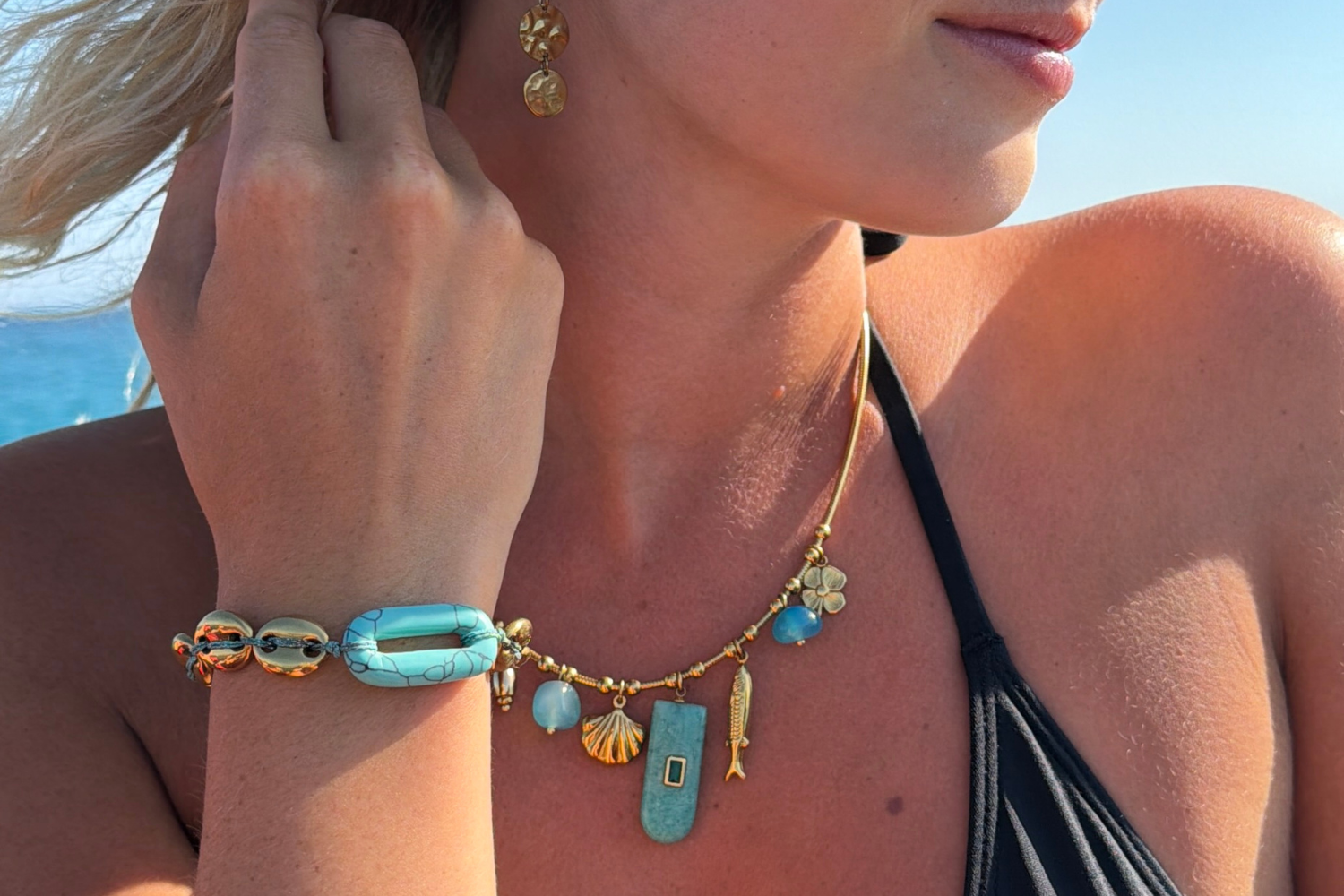 Eida Gold Coastal Charm Necklace worn layered, featuring Amazonite and blue agate gemstone drops with shell, fish and flower charms on a waterproof 14k gold PVD chain.