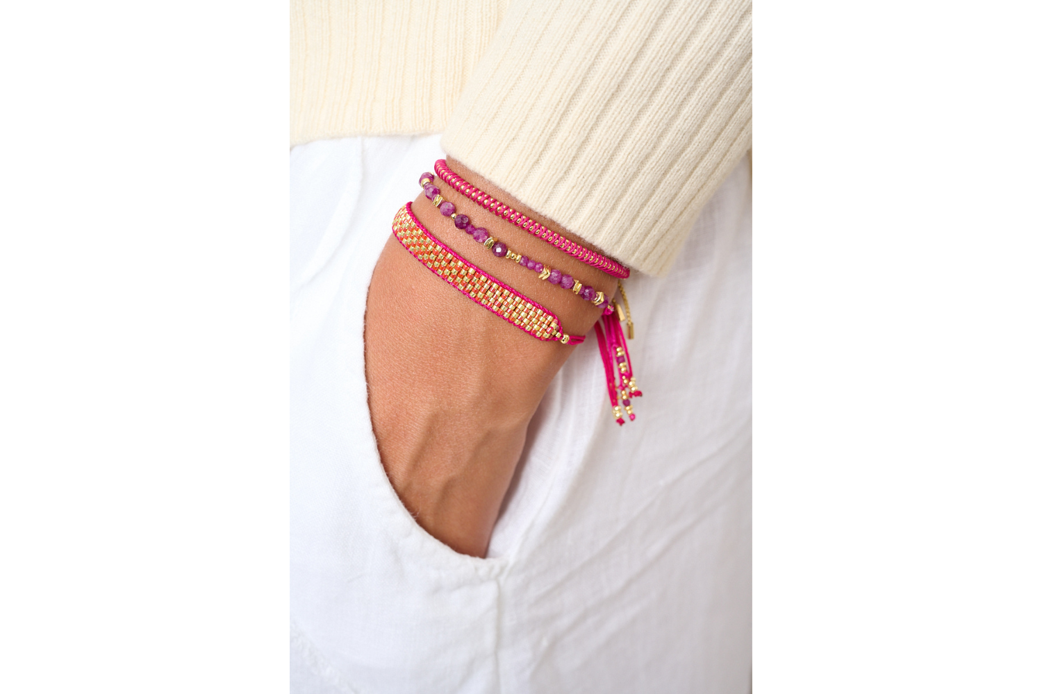 Emelia Raspberry Gold Braided Bracelet styled on a wrist, showcasing its vibrant raspberry hue, gold details, and a playful boho aesthetic, perfect for stacking or wearing solo.