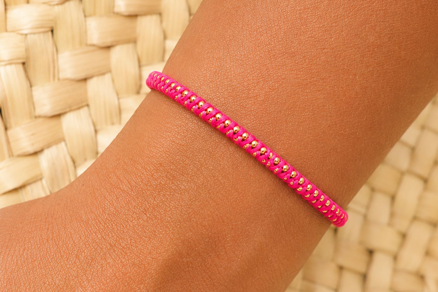 Emelia Woven Gold & Hot Pink Bracelet styled on the wrist with bold hot pink cord and warm gold accents for playful boho stacking.
