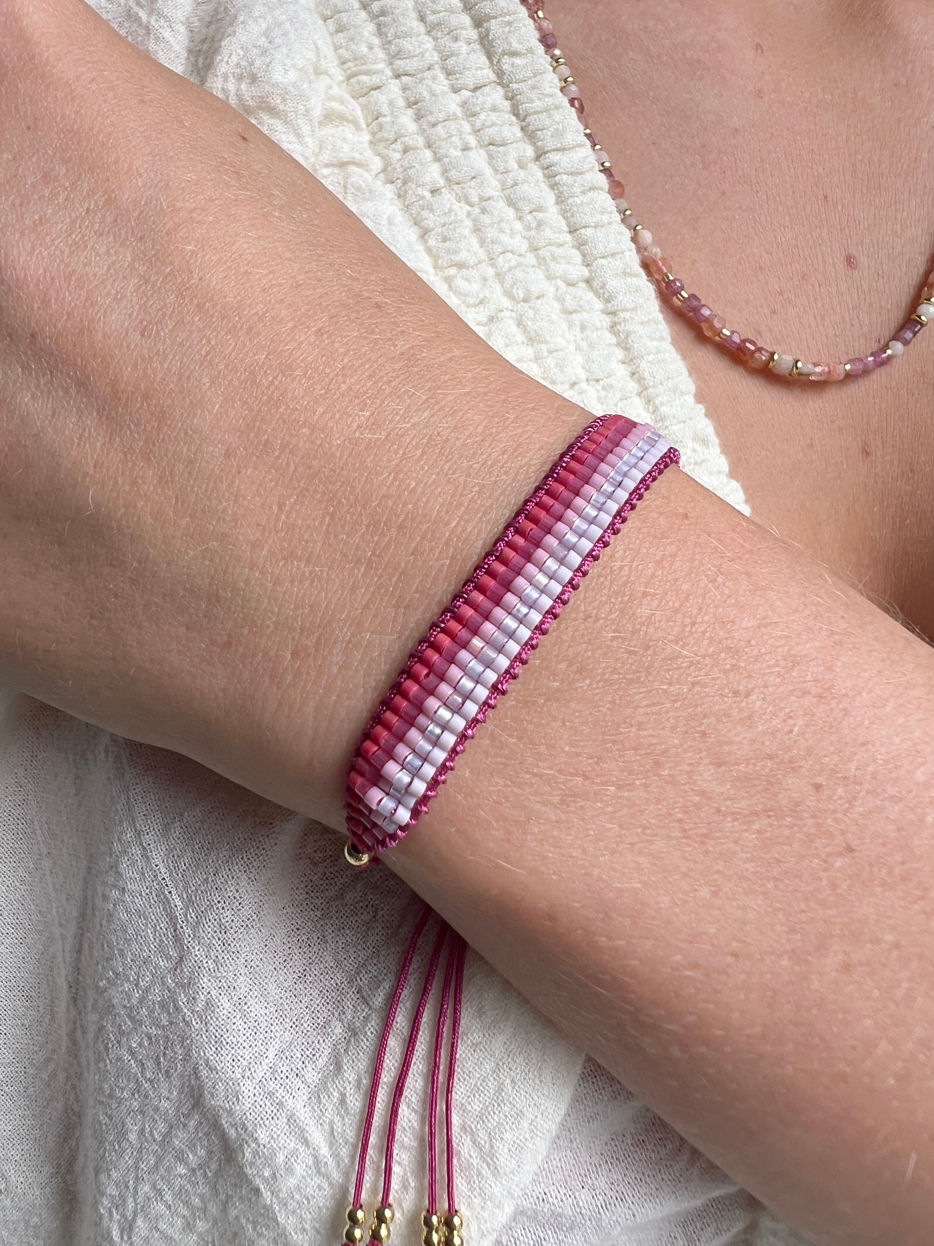 Faye Pink & Gold Miyuki Beaded Friendship Bracelet styled on the wrist, layered with other boho bracelets for a vibrant, playful look.