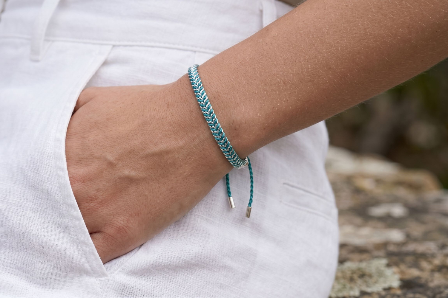 Iztac Teal Silver Woven Bracelet styled on the wrist, showcasing colourful teal woven detailing and polished silver accents for relaxed boho styling.