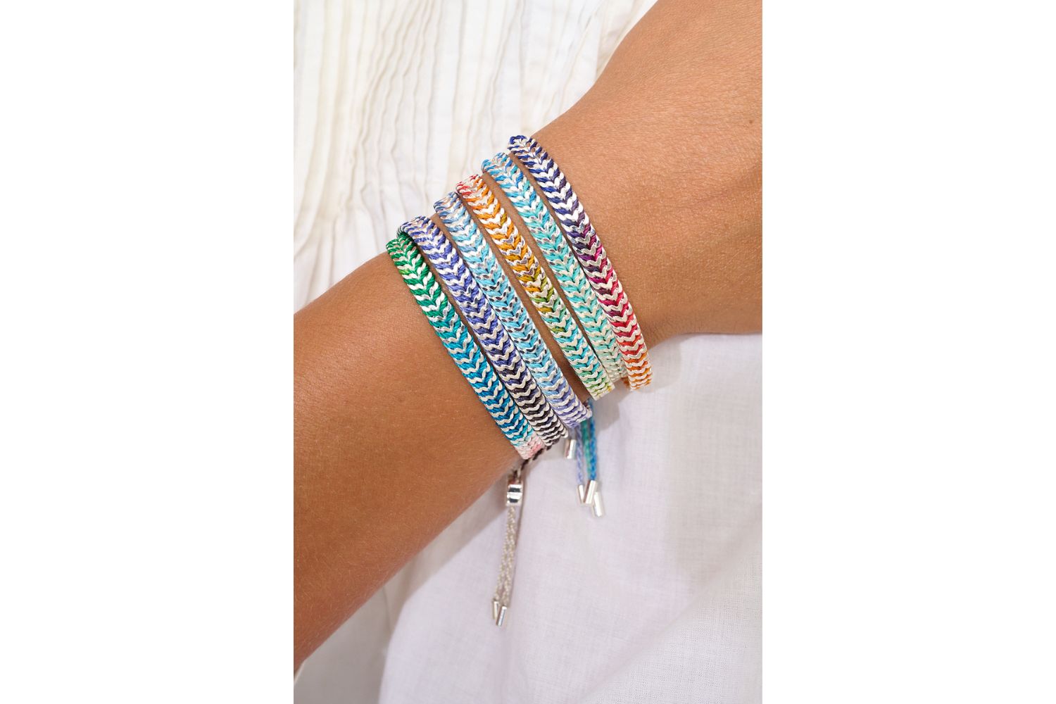 Iztac Turquoise Ombre Silver Braided Bracelet styled on the wrist, showcasing ombre purple threads and shimmering gold chevron details.