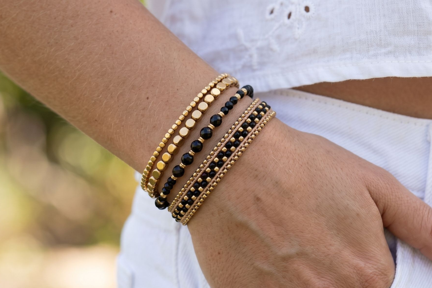 Montserrat Black Spinel and Gold Bracelet Stack styled on the wrist, showcasing faceted black spinel gemstones, chunky gold textures and layered woven bracelet details.