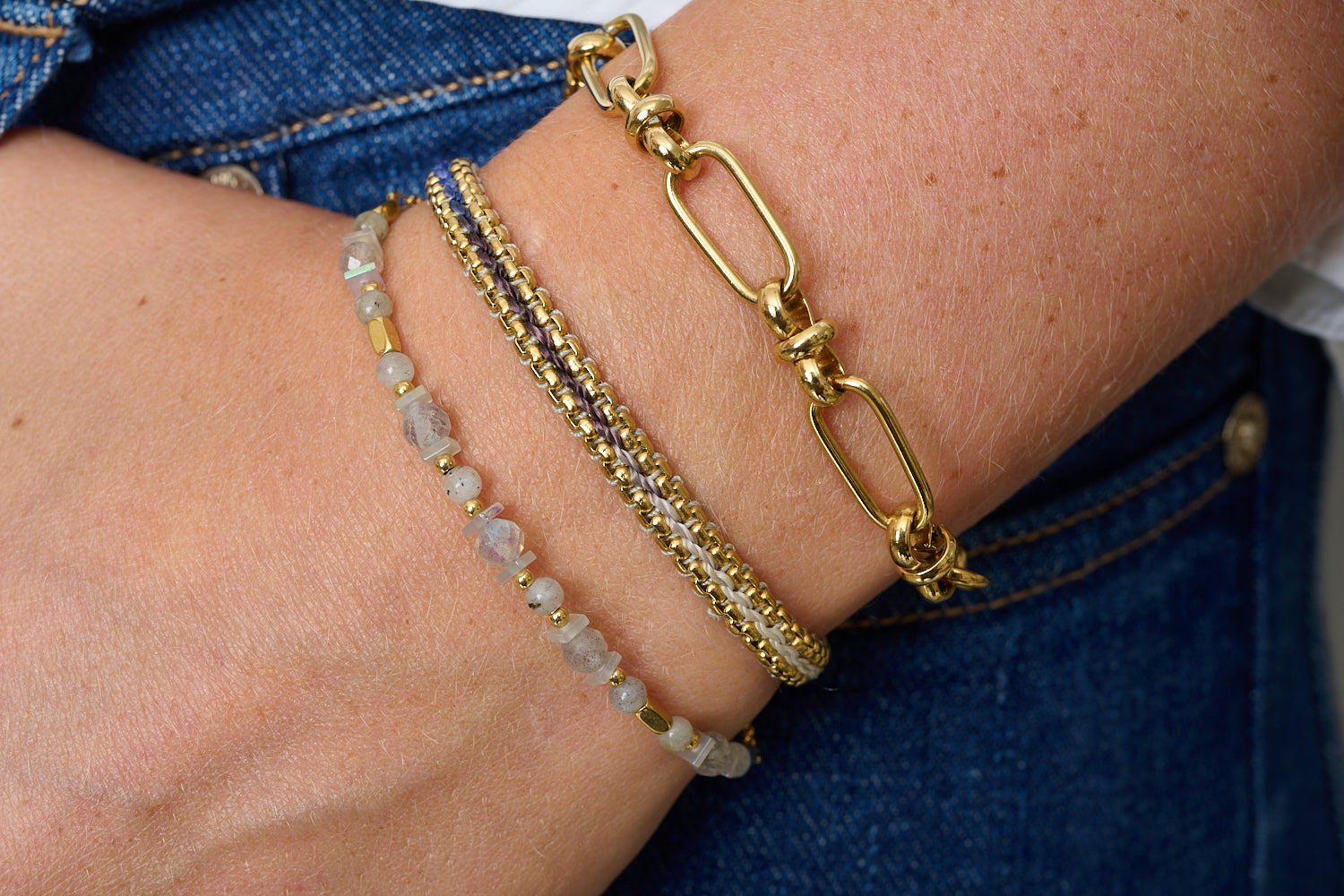Mordazo labradorite and gold bracelet stack styled on wrist, iridescent stones, chunky gold chain and denim-blue braid for relaxed luxe.