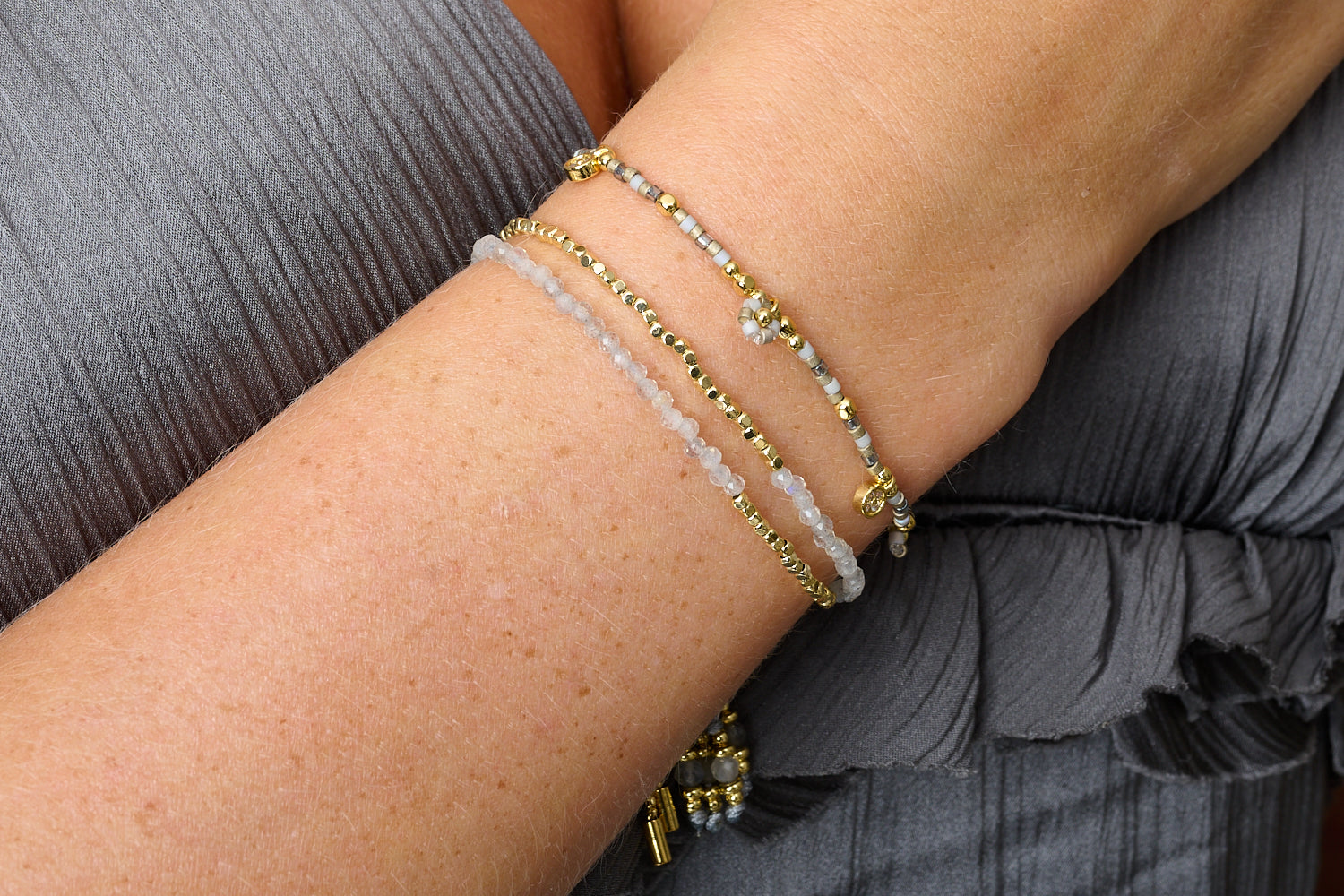 Layered bracelet look featuring the Rania Grey & Gold Beaded Charm Bracelet styled with neutral tones and golden accents.