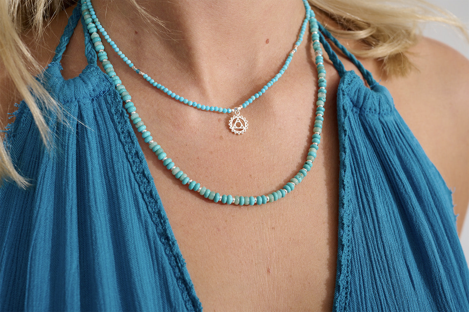 Turquoise Howlite, Apatite & Silver Throat Chakra Necklace styled on the neckline, showcasing its vibrant blue gemstones, silver accents, and meaningful chakra charm.
