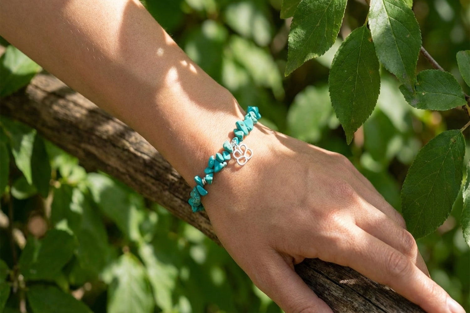 Turquoise Howlite beaded bracelet with silver accents displayed on a wooden surface outdoors with greenery and sunlight.
