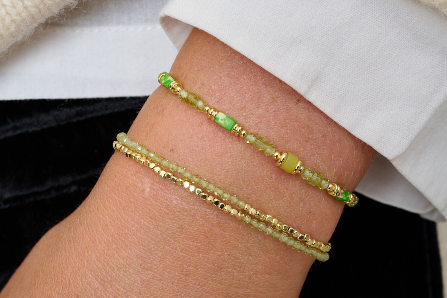 Ventana peridot bracelet duo styled in soft neutrals—gold accents and green gemstones for relaxed-luxe glow.