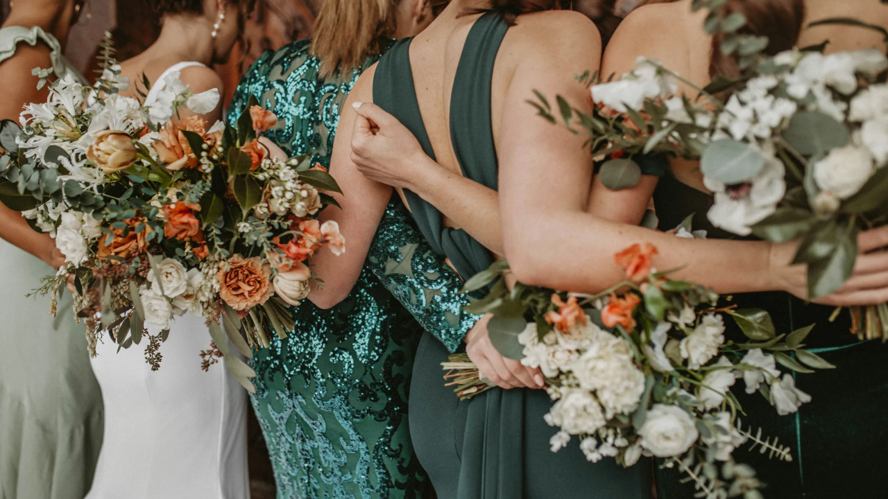 Bridesmaid group in deep emerald and forest green dresses at a moody woodland wedding