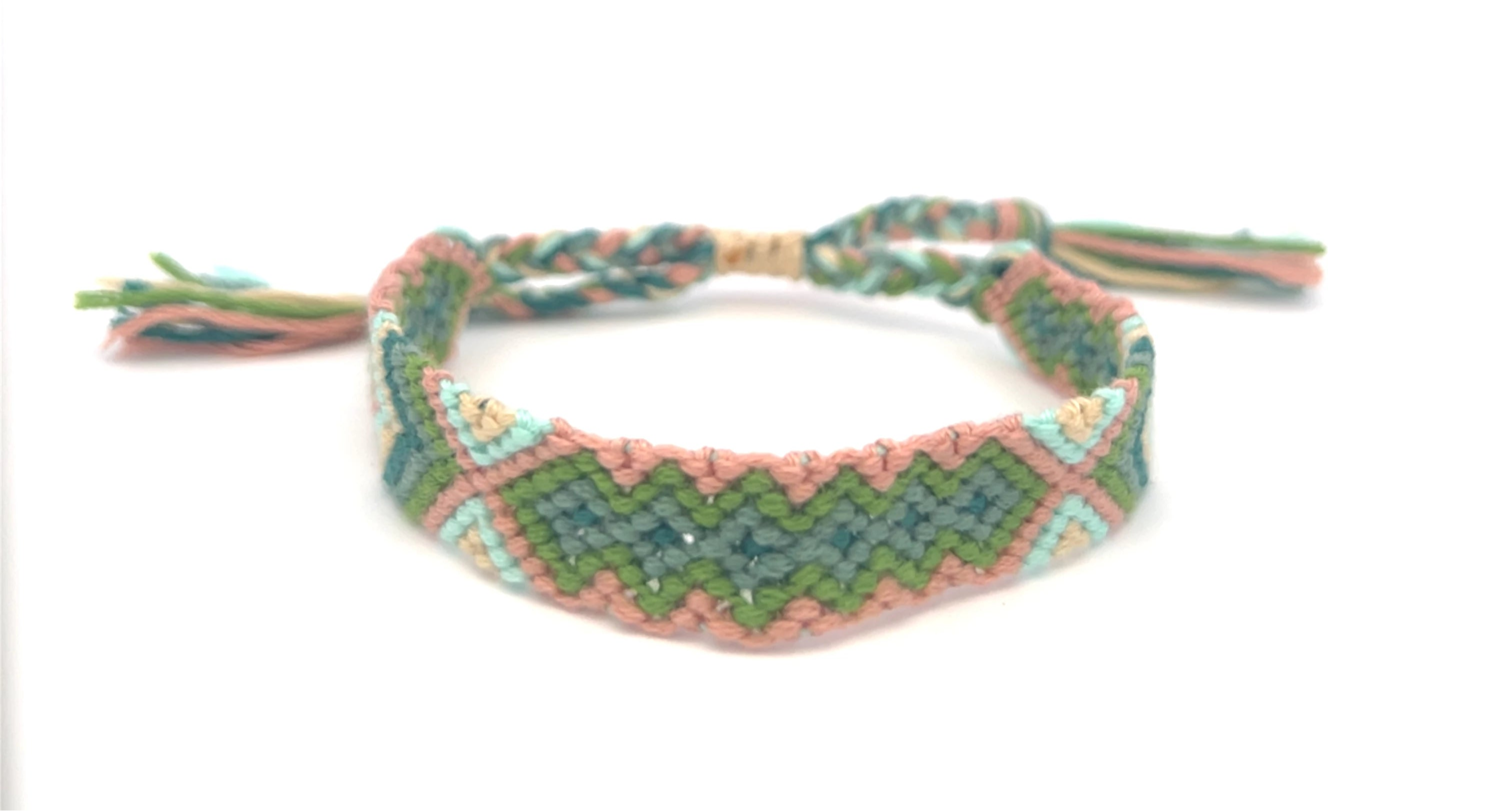 Braided friendship bracelet with pink and aqua green pattern on a white background