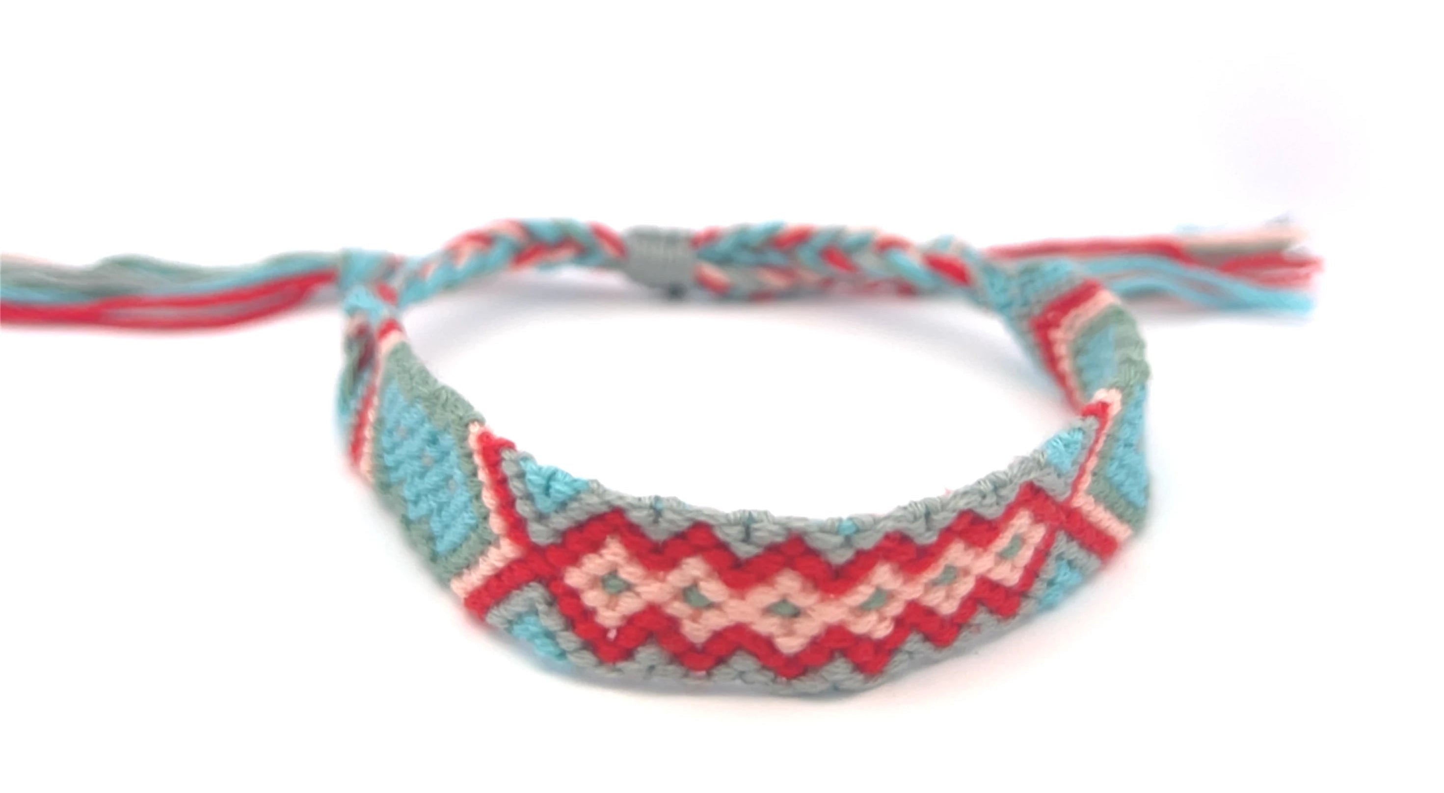 Woven aqua and pink braided friendship bracelet with geometric pattern on a white background