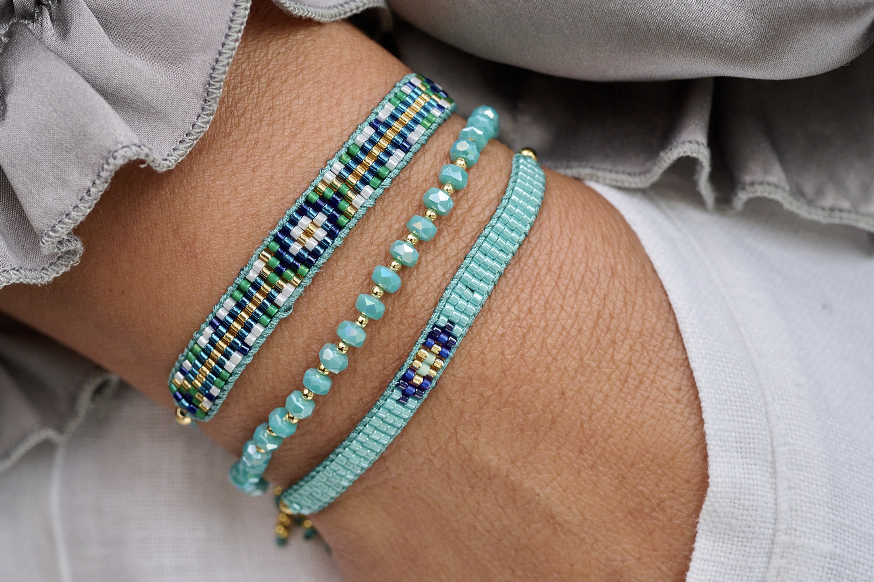 A lifestyle picture showcasing the jump aqua beaded bracelet paired alongside Fantasy aqua beaded bracelet and prunus crystal stretch bracelet for perfect styling