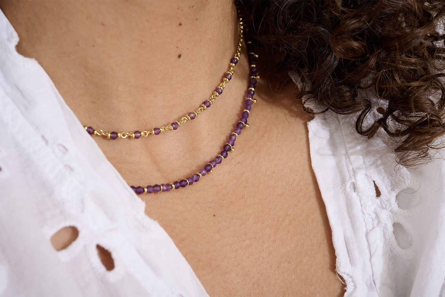 Lifestyle picture of the purple Amethyst  beaded necklace layered stylishly with Salus Amethyst beaded necklace worn with a white blouse.