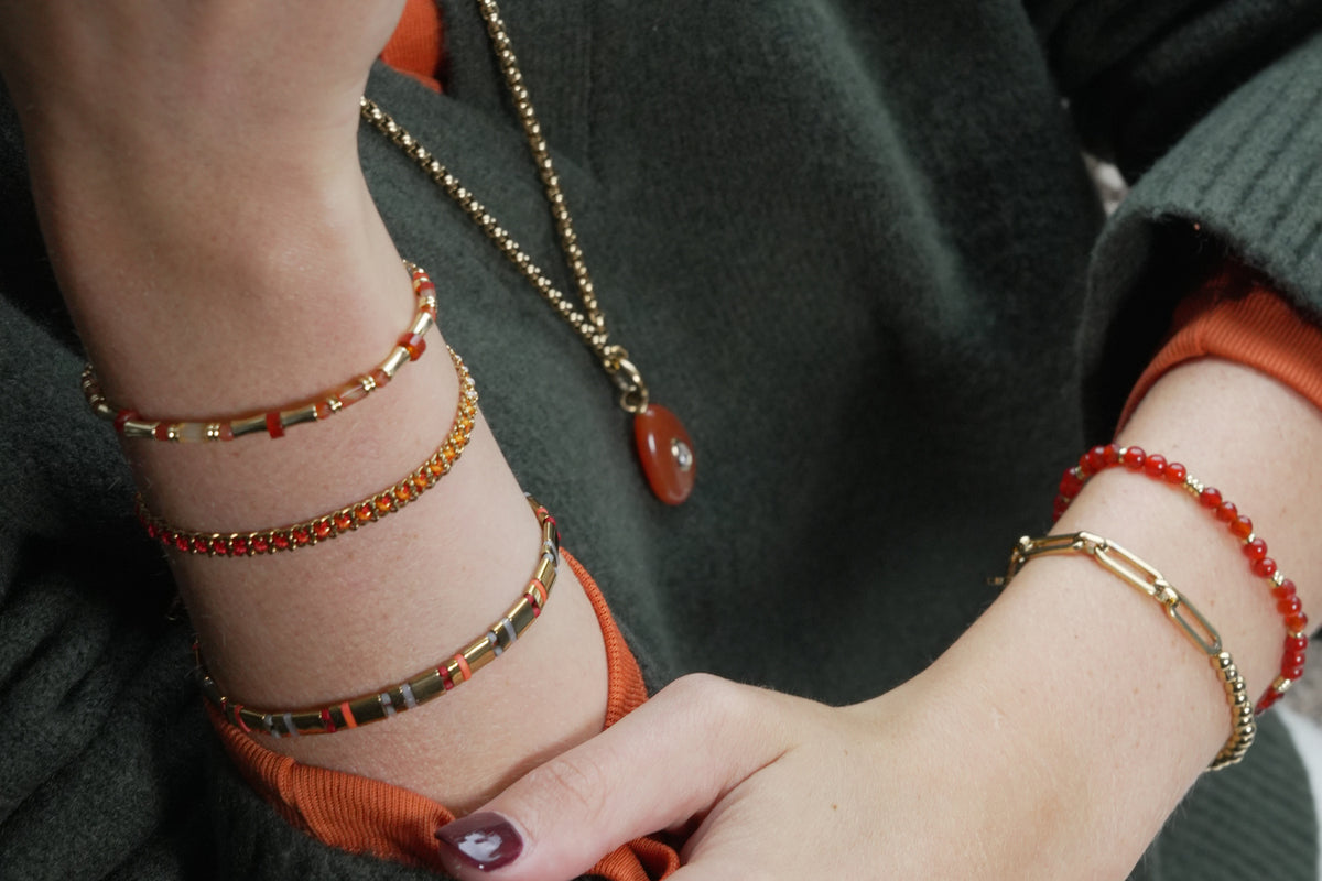Chiara gold and orange agate gemstone bracelet by Boho Betty – styled in a stack, a gold orange agate beaded slider bracelet