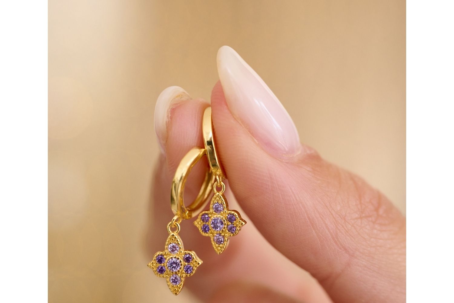 Close up lifestyle image showcasing the sparkle of Boho Betty's  amethyst colored CZ sterling silver Huggies with gold accents. The perfect gift for a girlfriend or Christmas Gift for her