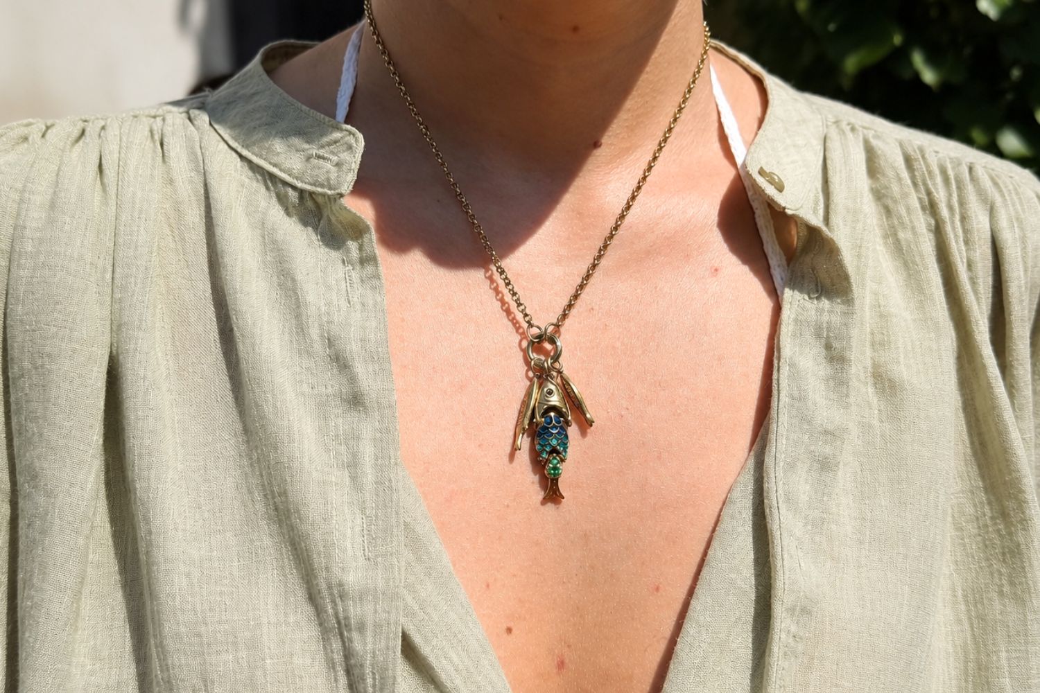 Anura Rainbow Cluster Gold Fish Necklace worn on the neckline, showcasing a trio of fish charms on a chunky waterproof 14k gold PVD charm carrier chain inspired by the ocean.