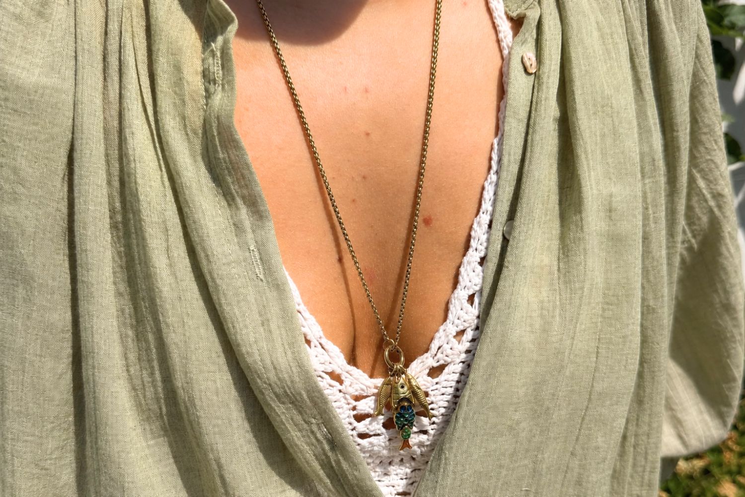 Anura Rainbow Cluster Gold Fish Necklace Long worn layered over clothing, showcasing three fish charms on a long waterproof 14k gold PVD charm carrier chain inspired by the ocean.