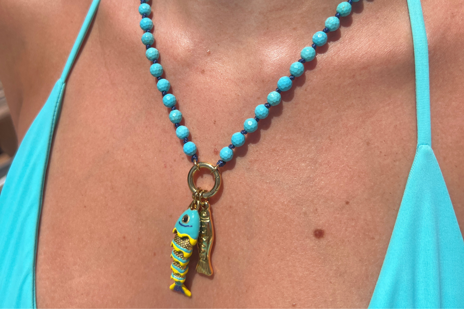 Ariel Turquoise Howlite Gold Waterproof Fish Charm Necklace worn layered with vibrant Turquoise Howlite gemstones, removable fish charms and waterproof 14k Gold PVD-coated stainless steel details.