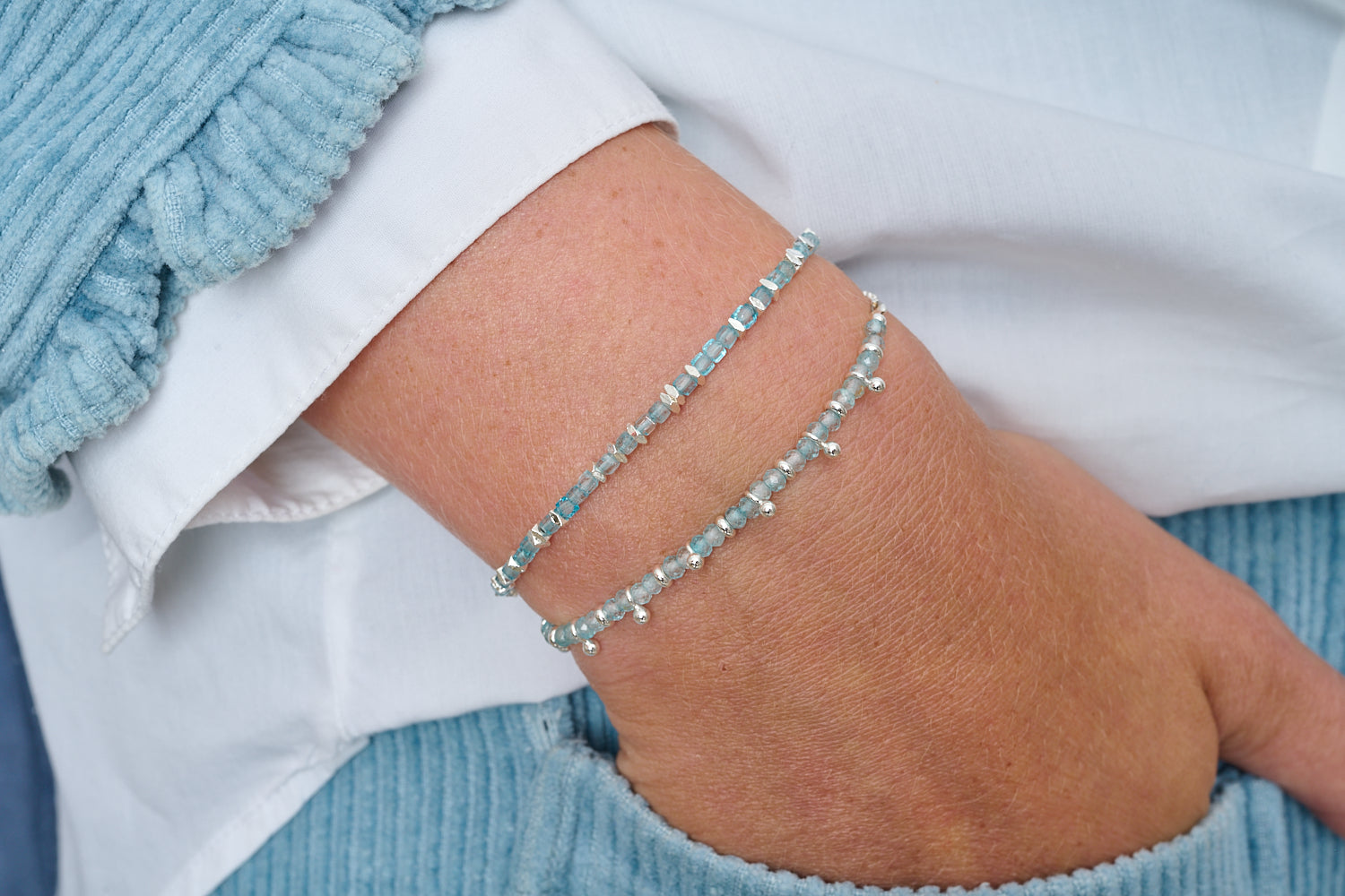 Ballena bracelet duo styled with cool neutrals, ocean-blue topaz and silver for a calm, modern glow.