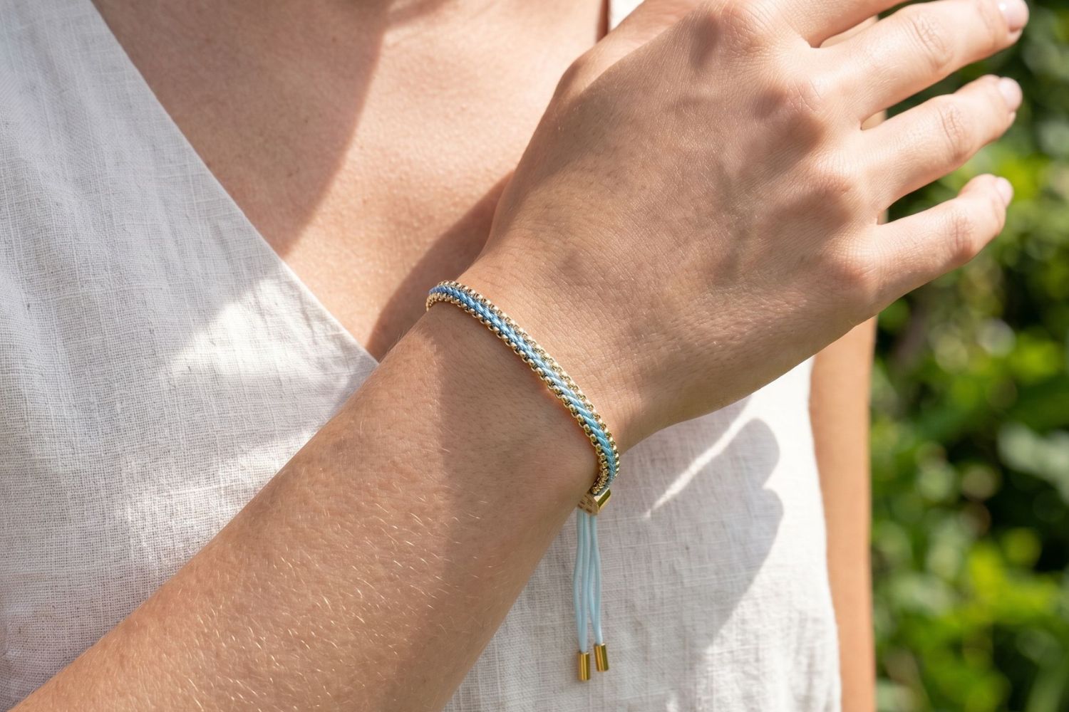 Bloom sky blue woven bracelet styled on the wrist, a light blue gold friendship bracelet perfect for stacking and everyday wear.