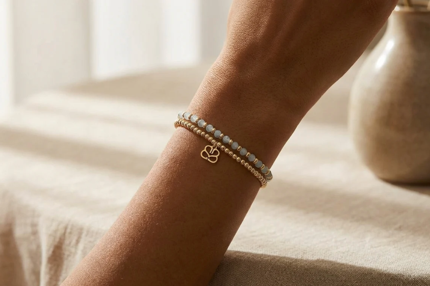 Close-up of Bluebell Gold & Aquamarine bracelet on diverse skin tones, showing faceted beads and gold accents, in a relaxed pose.