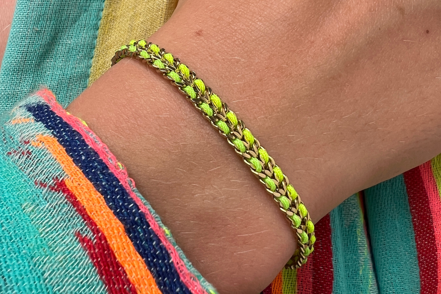 Cari neon lime woven bracelet styled on the wrist, a bold colourful gold friendship bracelet perfect for stacking and summer styling.
