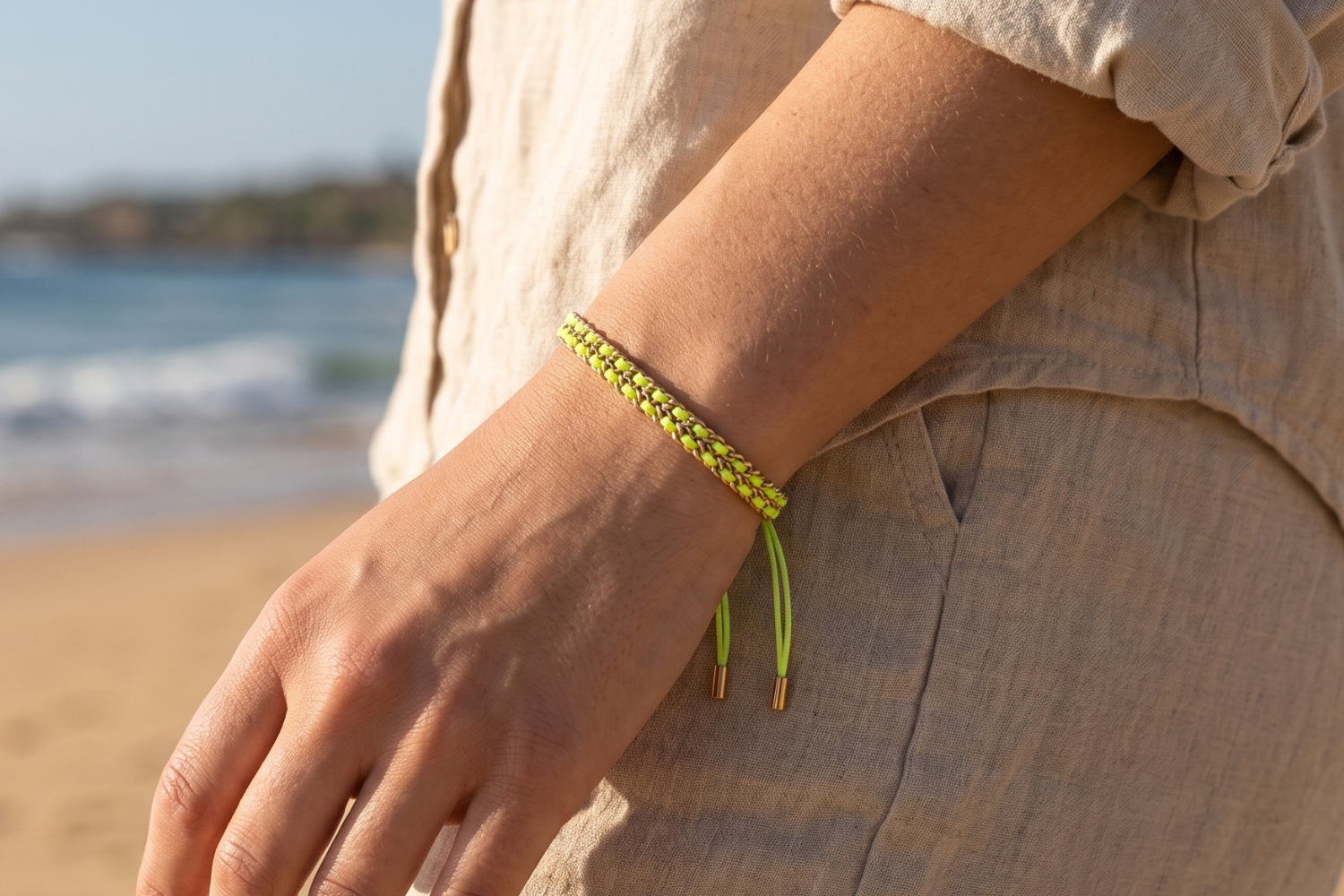 Cari neon lime woven bracelet styled on the wrist, a bold colourful gold friendship bracelet perfect for stacking and summer styling.