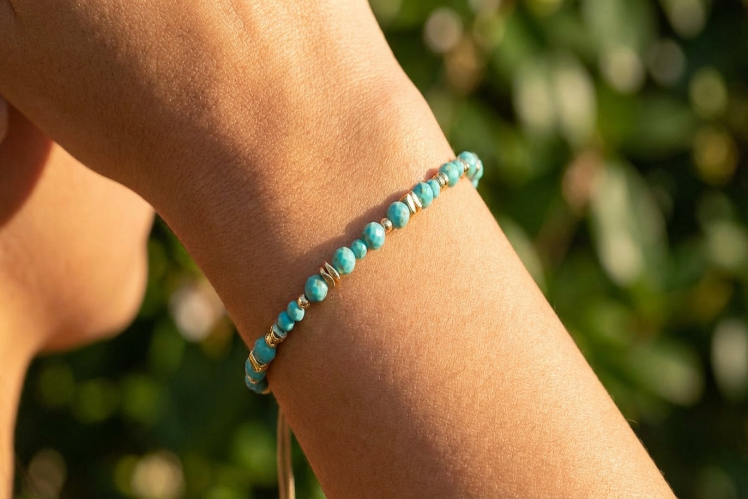 Close-up of Bliss Gold Slider Turquoise Beaded Bracelet on female wrist highlighting chain and charm details in sunlight.