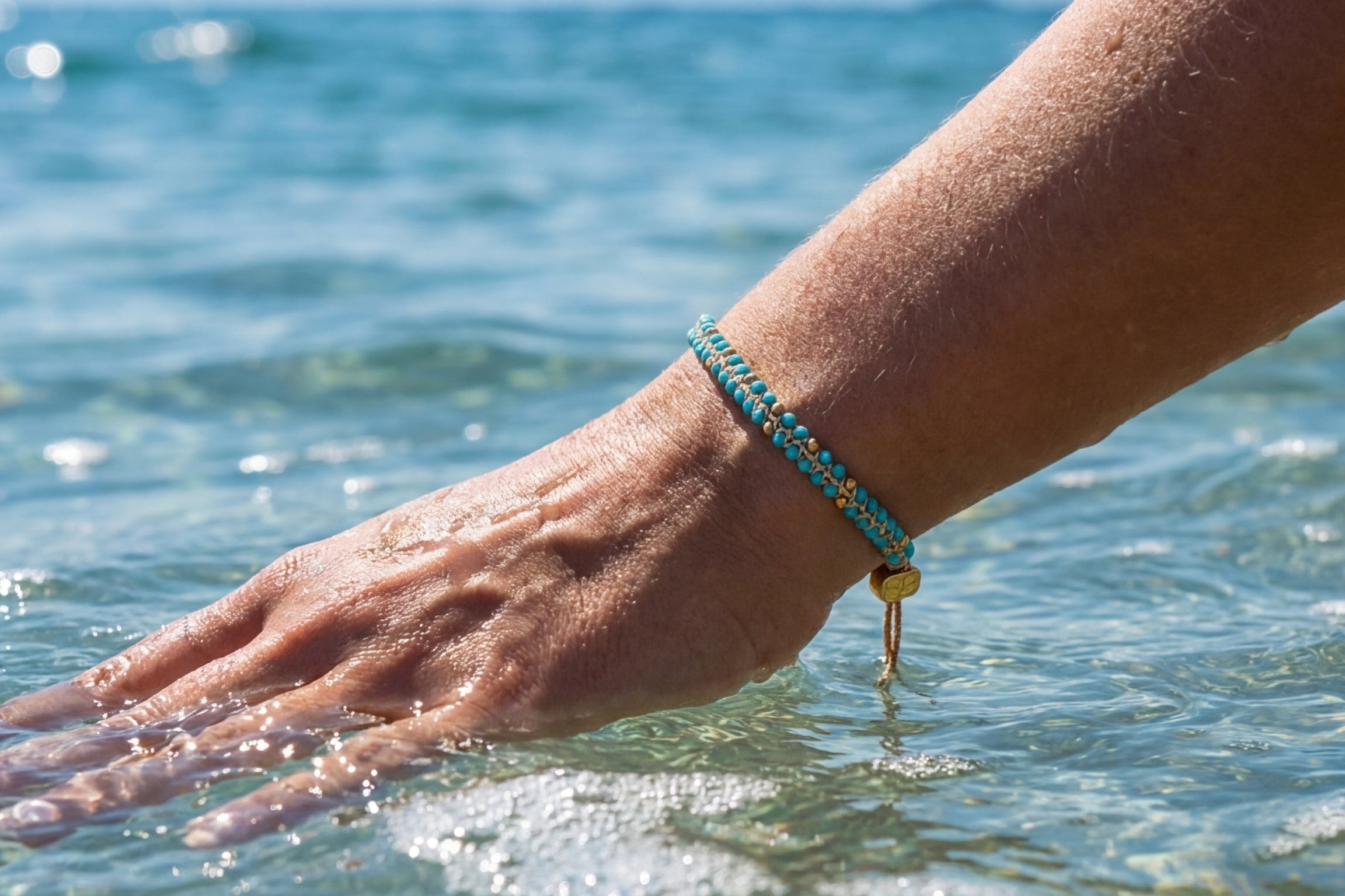 Close-up of the Cordelia Gold & Turquoise Braided Bracelet with intricate beads and adjustable slider, evoking summer vibes.