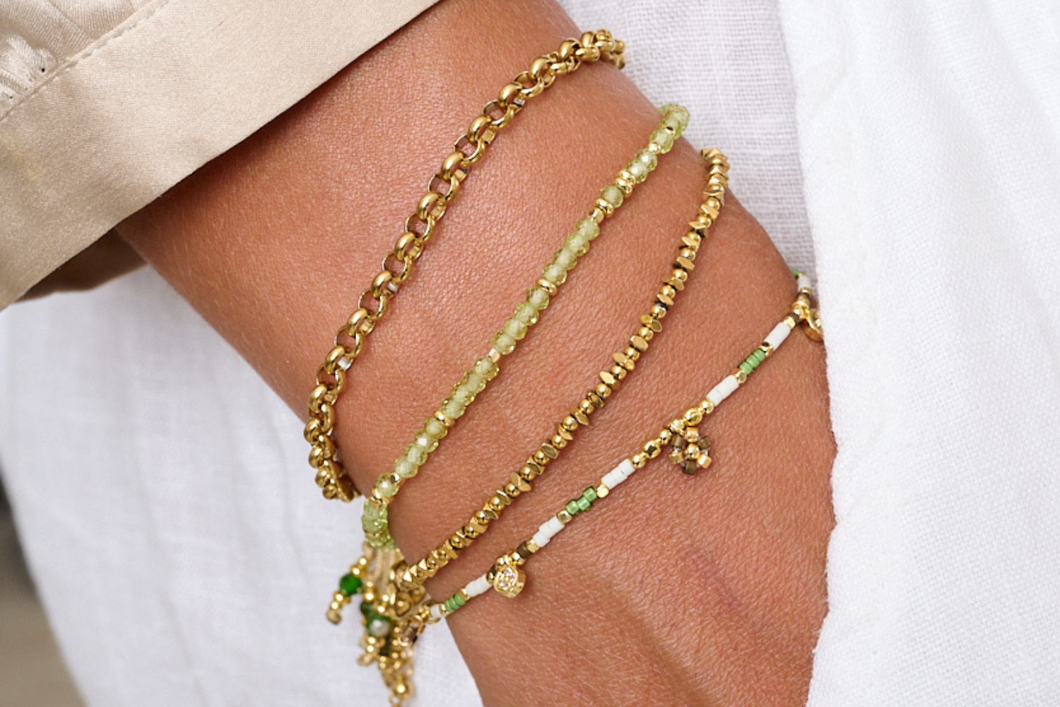 Dash Gold & Peridot Beaded Charm Bracelet styled on the wrist, showcasing soft green gemstone sparkle, BB charm, and boho-inspired golden accents.
