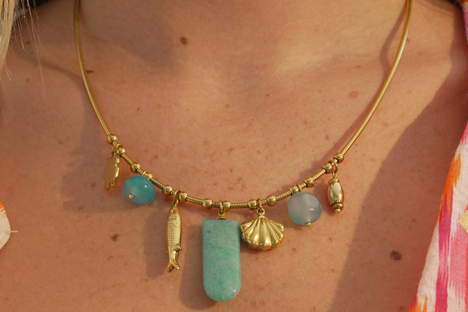 Eida Gold Coastal Charm Necklace worn layered, featuring Amazonite and blue agate gemstone drops with shell, fish and flower charms on a waterproof 14k gold PVD chain.