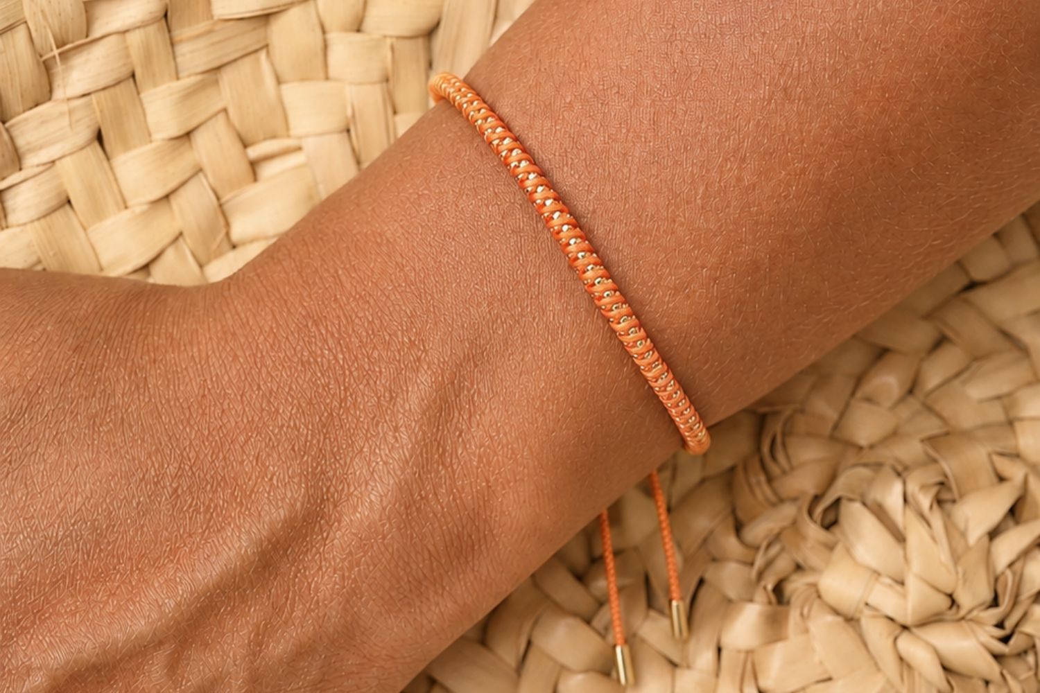 Emelia Gold & Neon Orange Woven Bracelet styled on the wrist with neon orange cord and warm gold detailing for bold boho stacking.