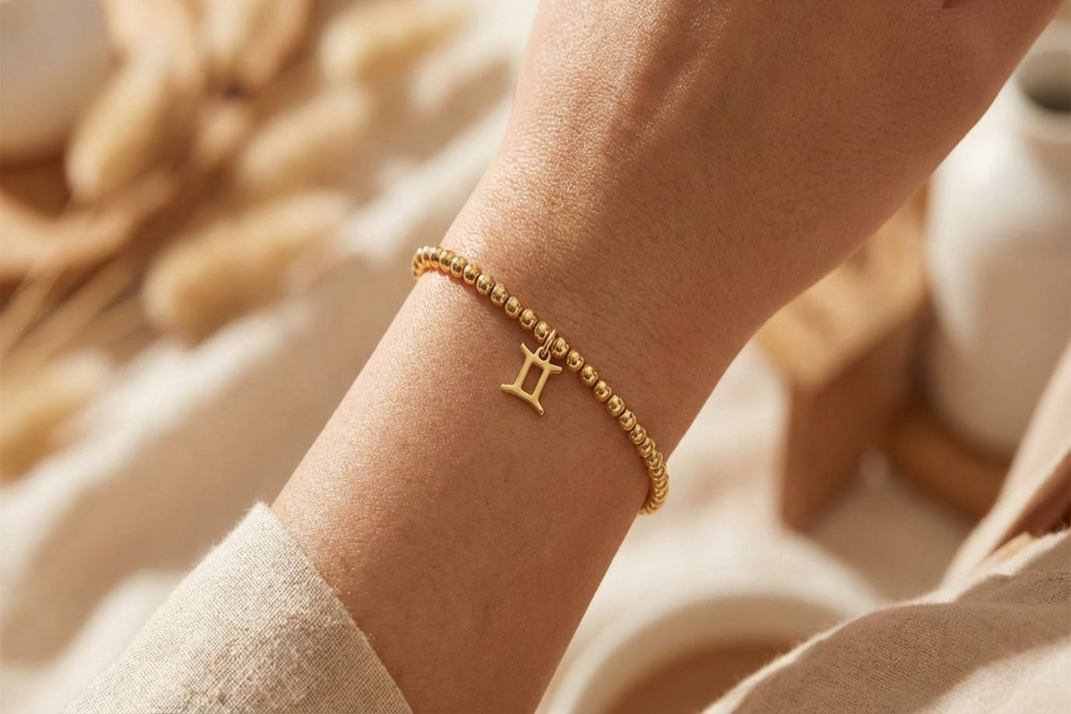 Gold Gemini zodiac charm bracelet laid on textured surface showcasing delicate chain and small charm details.