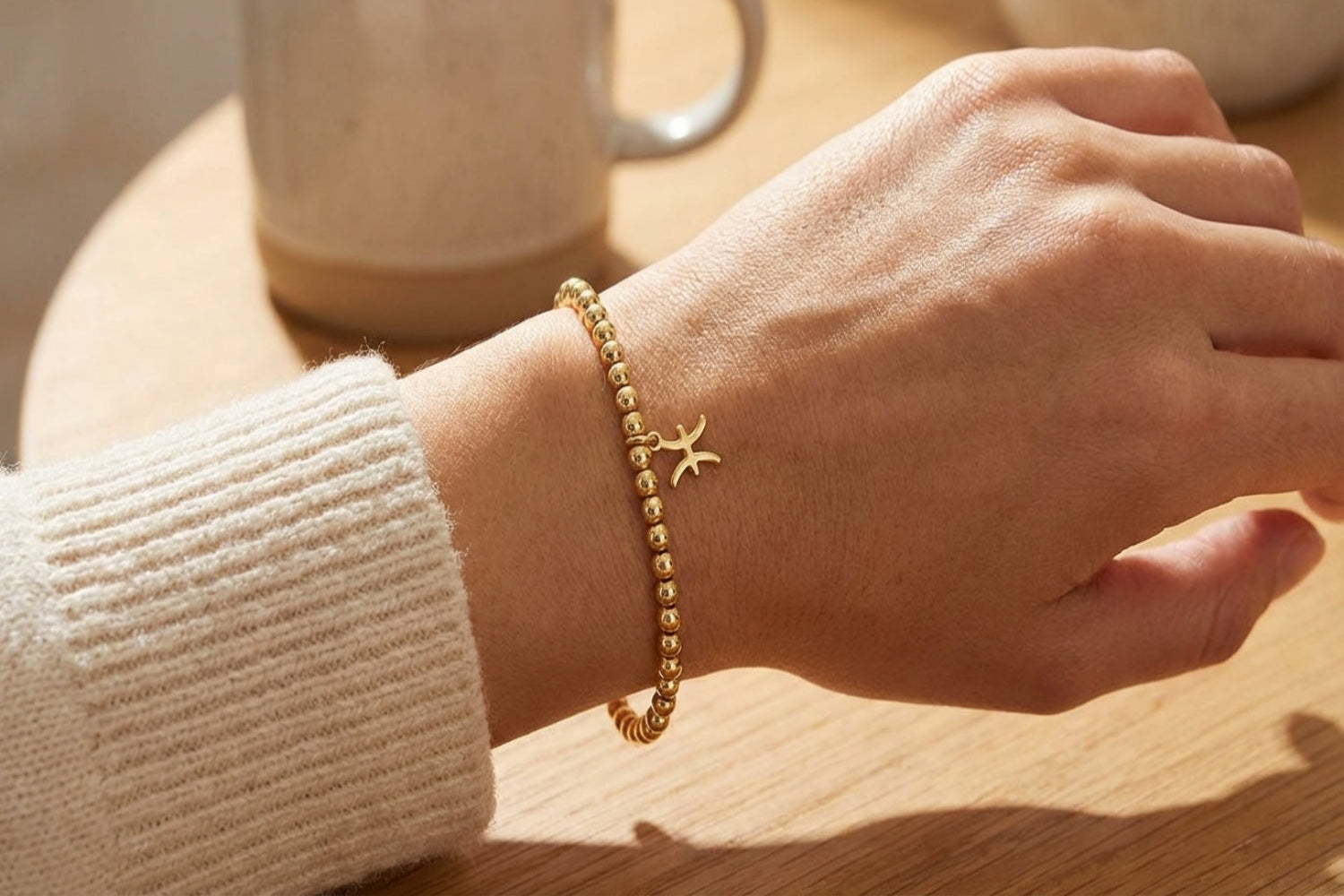 Gold Pisces zodiac charm bracelet on smooth surface highlighting bead micro-details and warm golden hue.