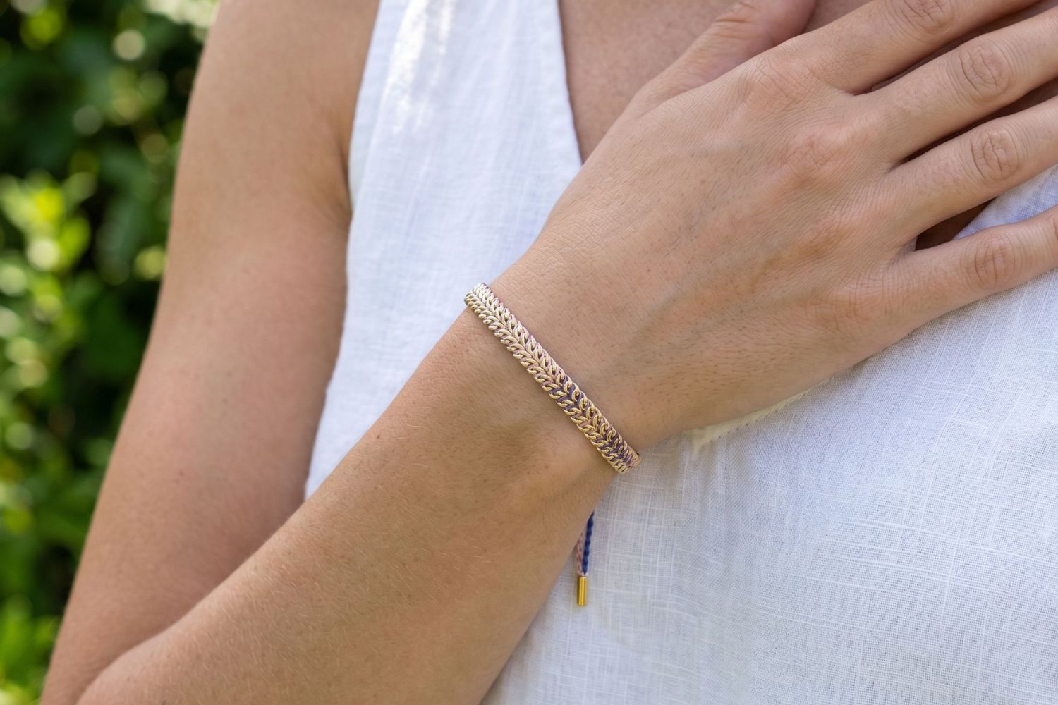 Iztac lilac and blush woven bracelet styled on the wrist, a soft pastel gold friendship bracelet perfect for stacking and everyday wear.
