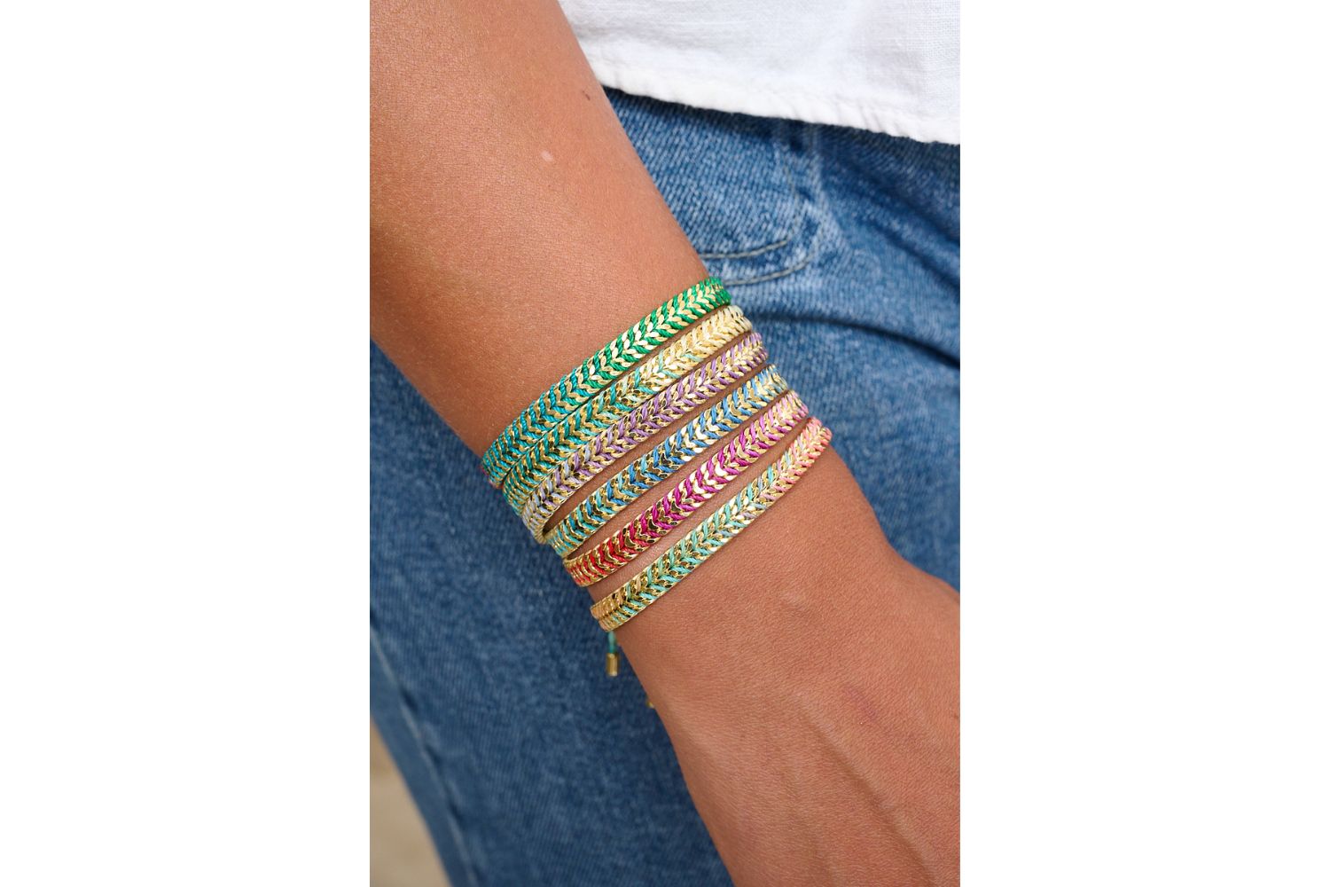 Iztac Turquoise Ombre Gold Braided Bracelet styled on the wrist, showcasing ombre purple threads and shimmering gold chevron details.
