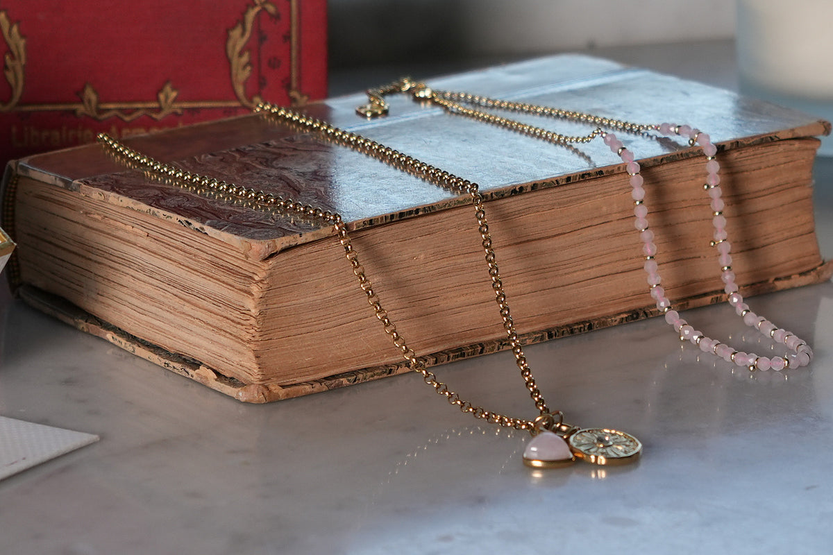 Kallisto Gold Rose Quartz Gemstone Pendant styled on the Eira reversible gold necklace, draped over a vintage book
