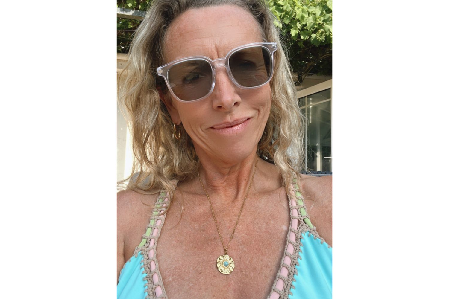 Nerissa Amulet Necklace styled with beachwear and gold jewellery layers, glowing in natural light.
