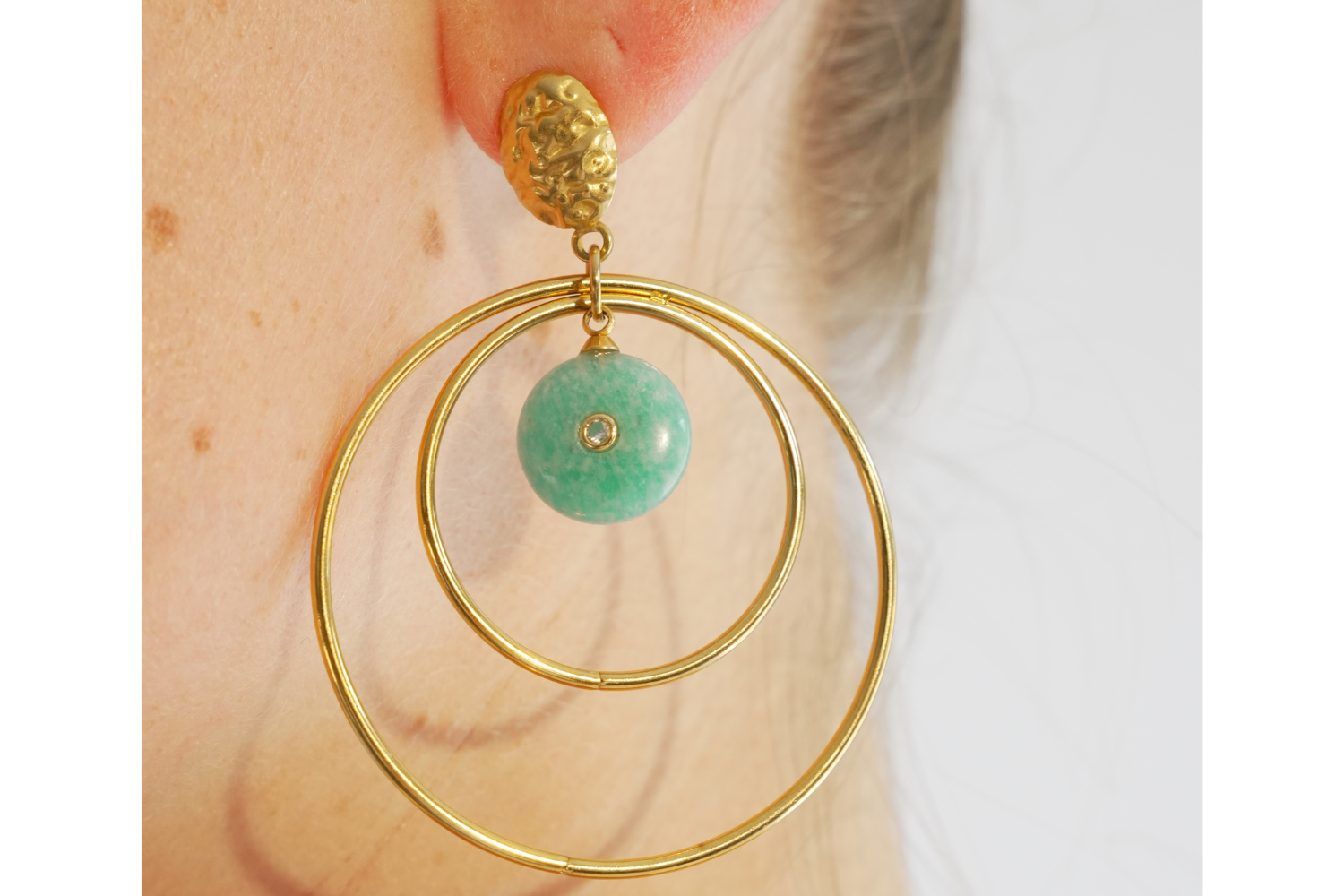 Model wearing Onda Amazonite Gold Statement Earrings featuring Amazonite gemstone drops, crystal accents and waterproof 14k Gold PVD double hoop design.