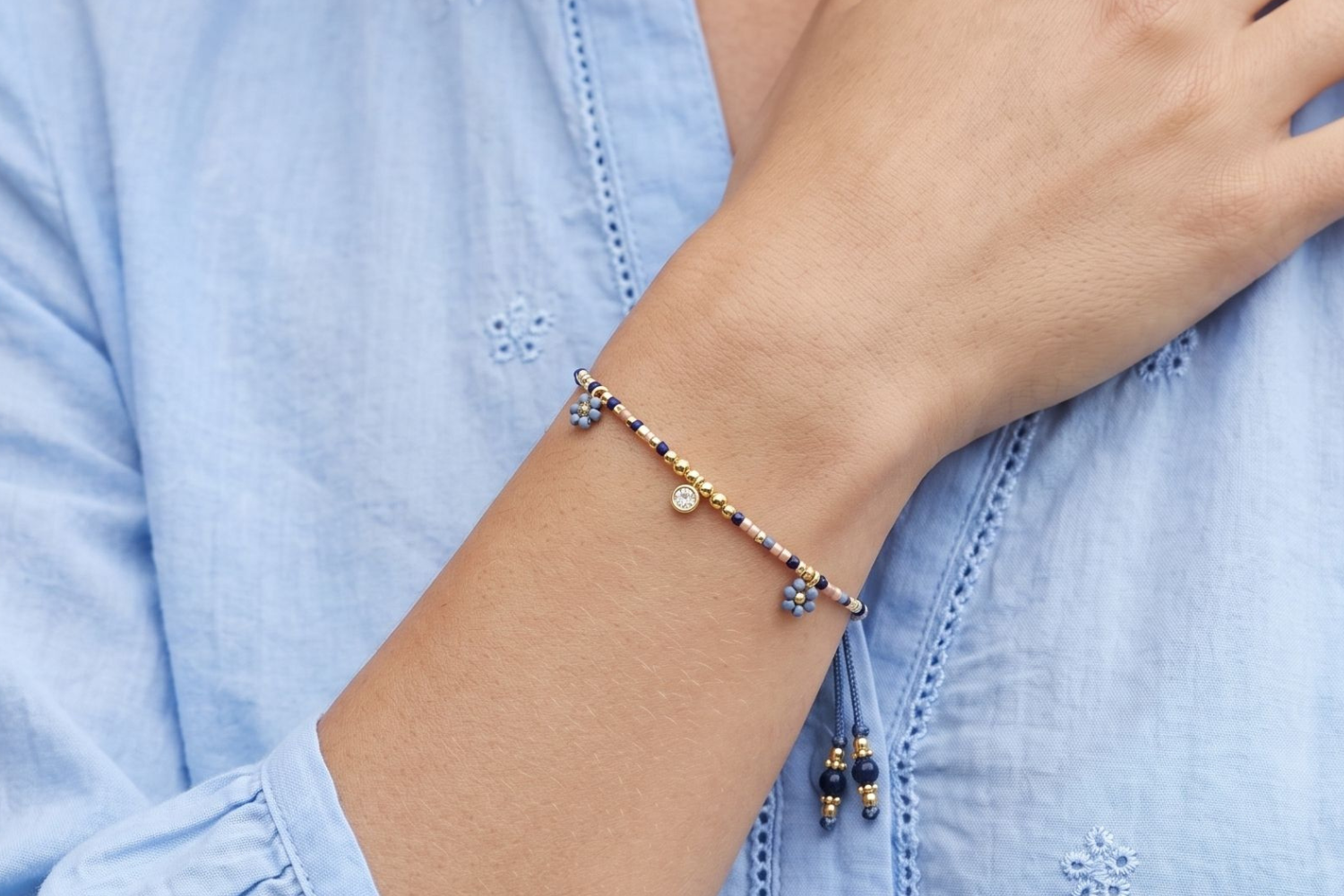 Rania Denim & Gold Beaded Charm Bracelet styled in a boho-inspired wrist stack with layered gold and blue-toned accessories.