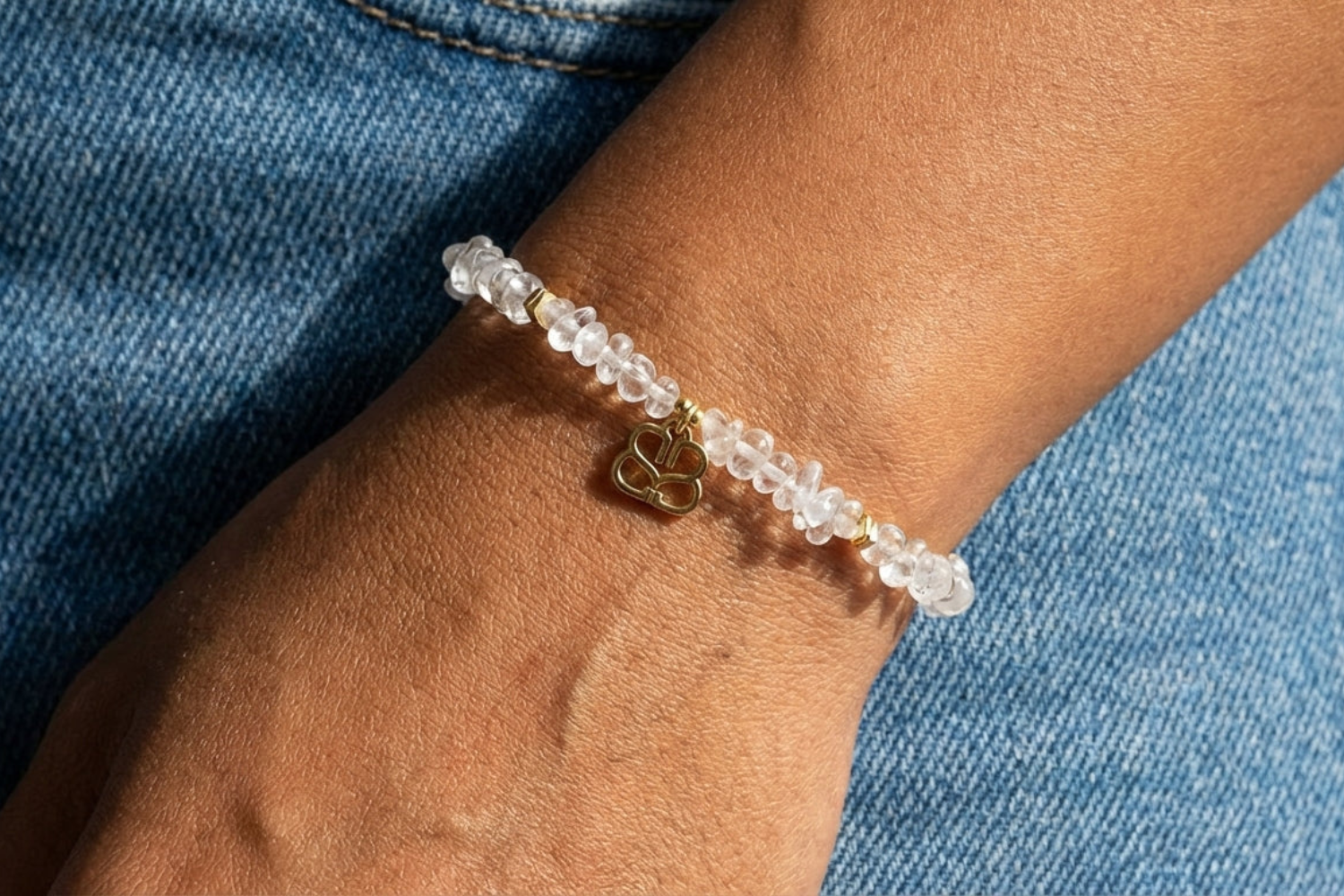 Minimalist scene of Sana Rock Crystal Bead Bracelet close-up on models wrist with denim background, highlighting crystal clarity and gold accents