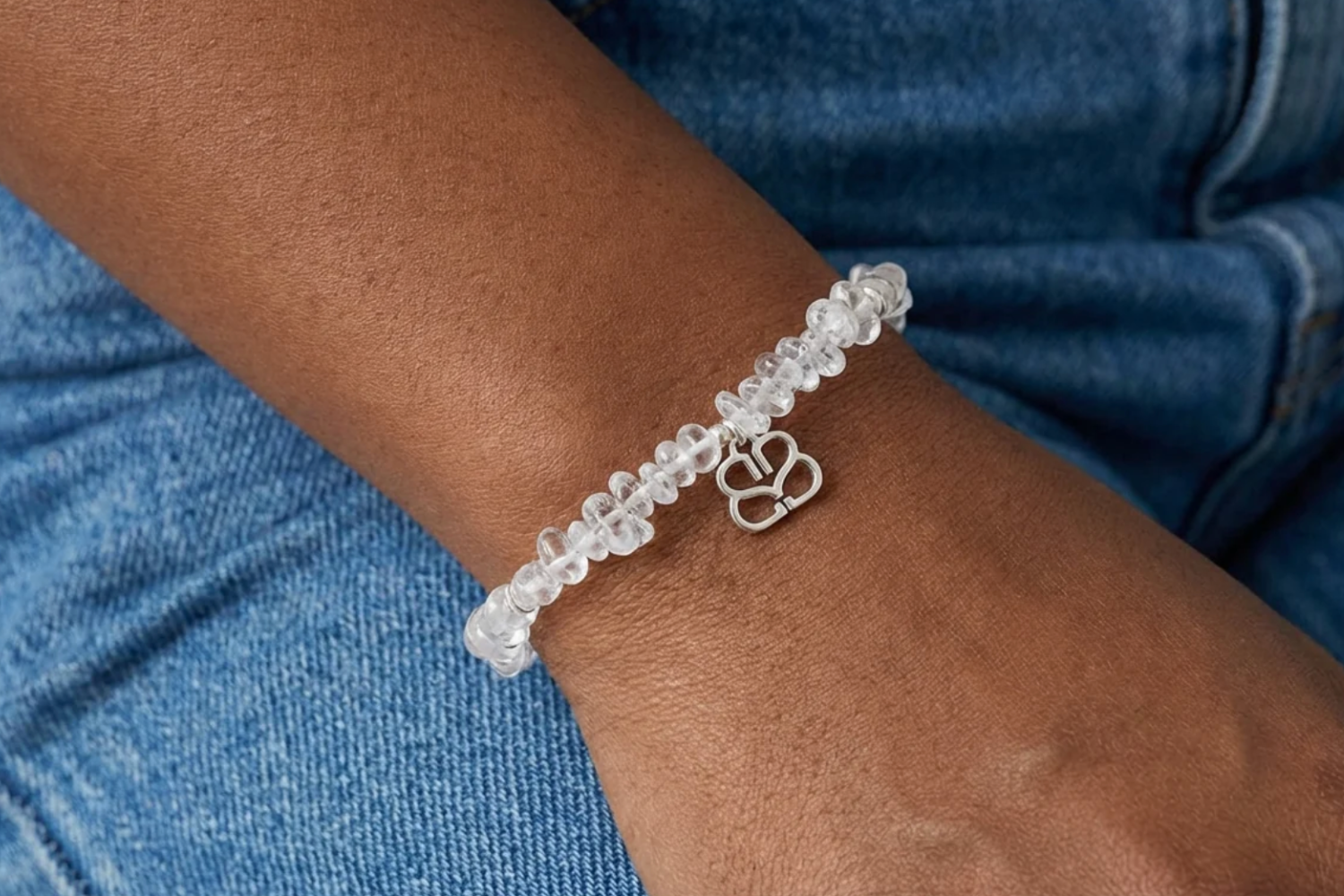 Close-up of model's wrist wearing Sana silver beaded rock crystal bracelet with denim background, highlighting crystal clarity and silver accents.