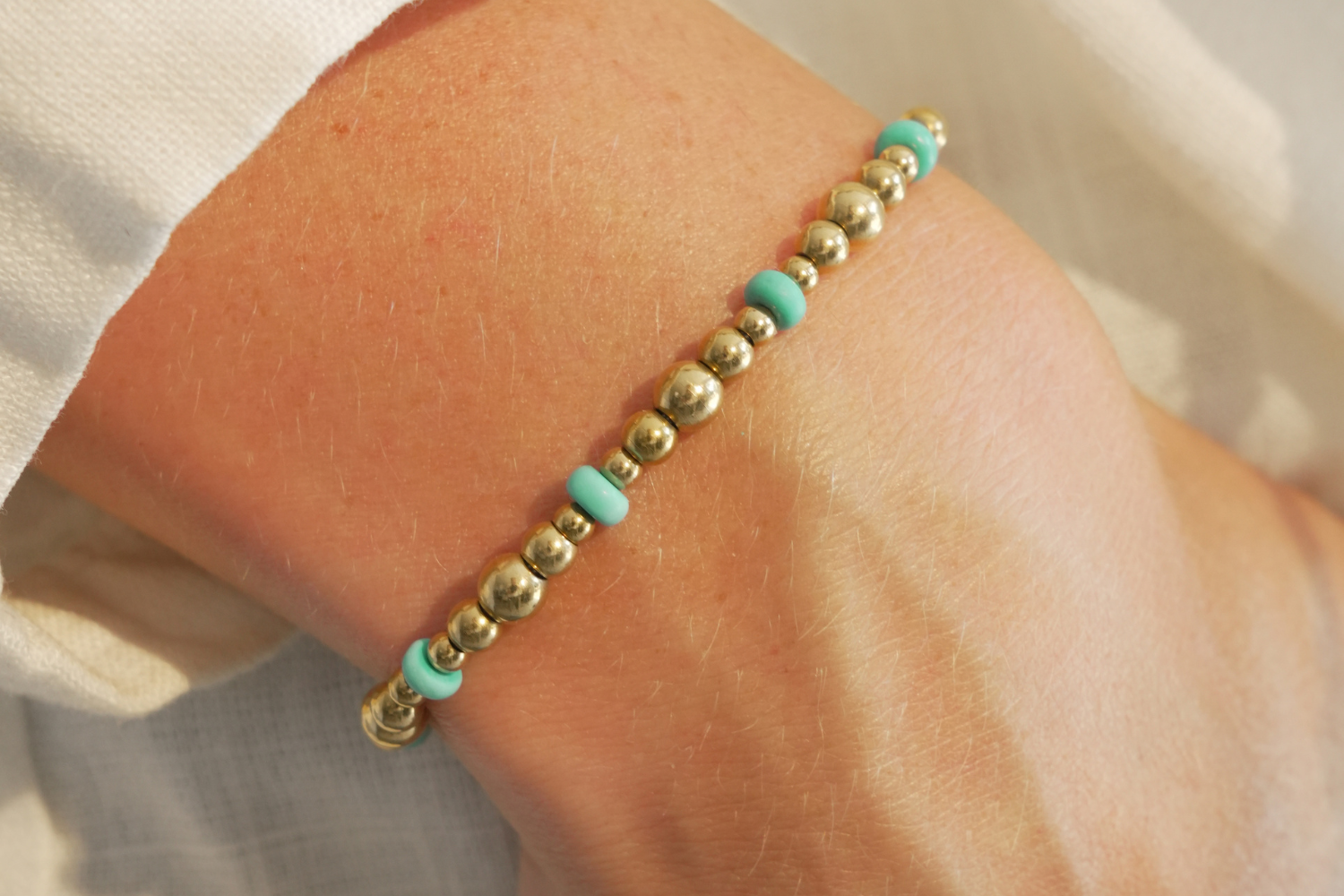 Sela Turquoise Howlite Gold Bead Slider Bracelet worn on the wrist featuring turquoise howlite gemstones, polished gold beads and an adjustable waterproof 14k gold PVD slider fastening.