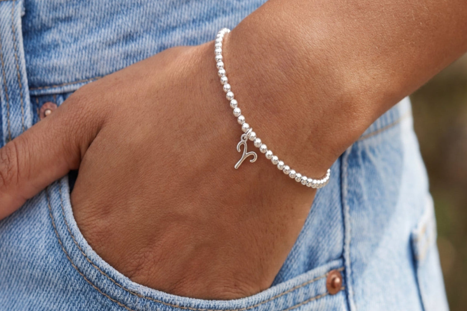 Silver Aries zodiac charm wristlet on marble surface, showcasing fine details and reflective silver finish in a well-lit, elegant setting.